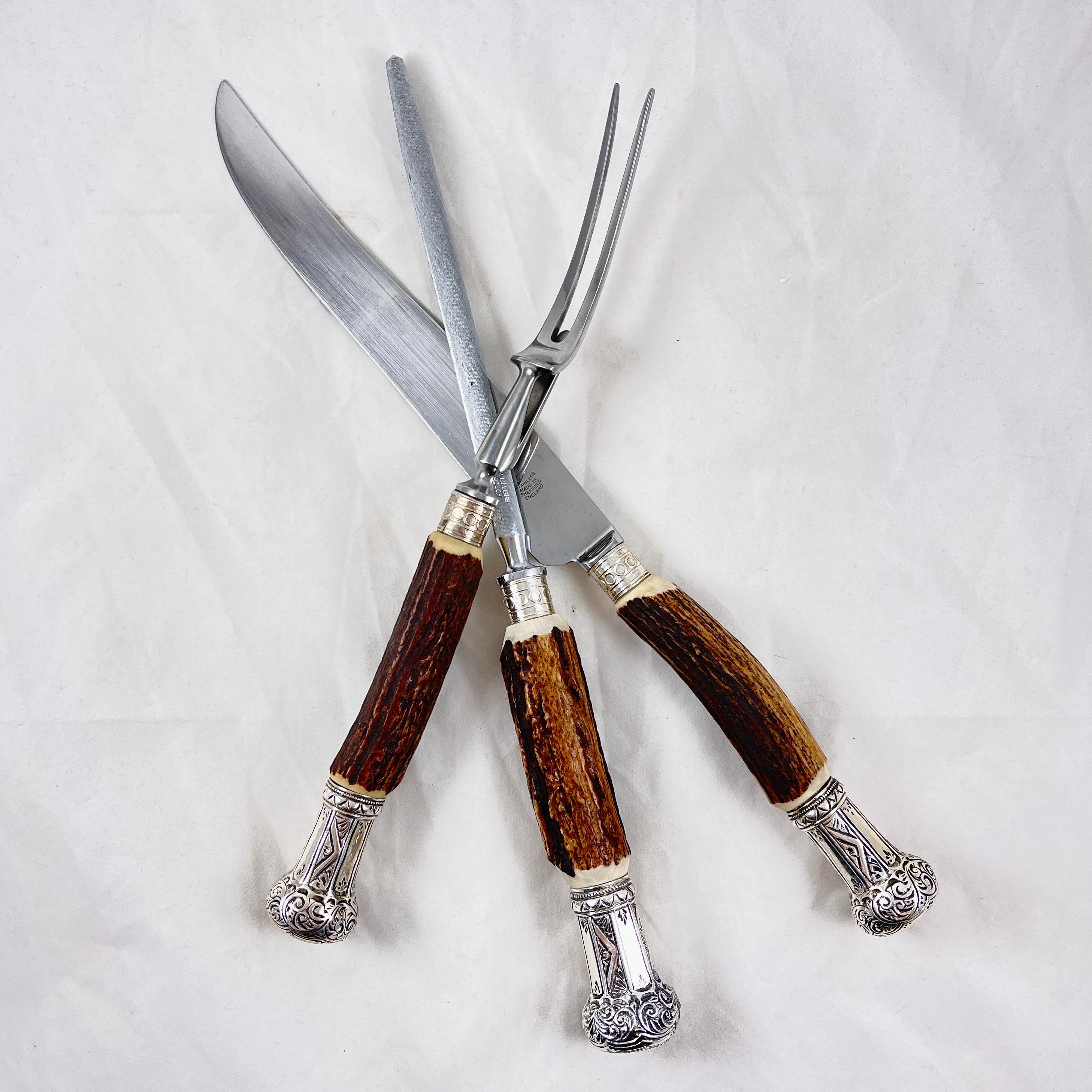A three piece carving set with Stag Antler handles and Sterling Silver ferrules and end caps, Sheffield, England, circa mid 20th Century.

Impressively sized, the set consists of a long carving knife, fork, and sharpening steel.
A beautifully
