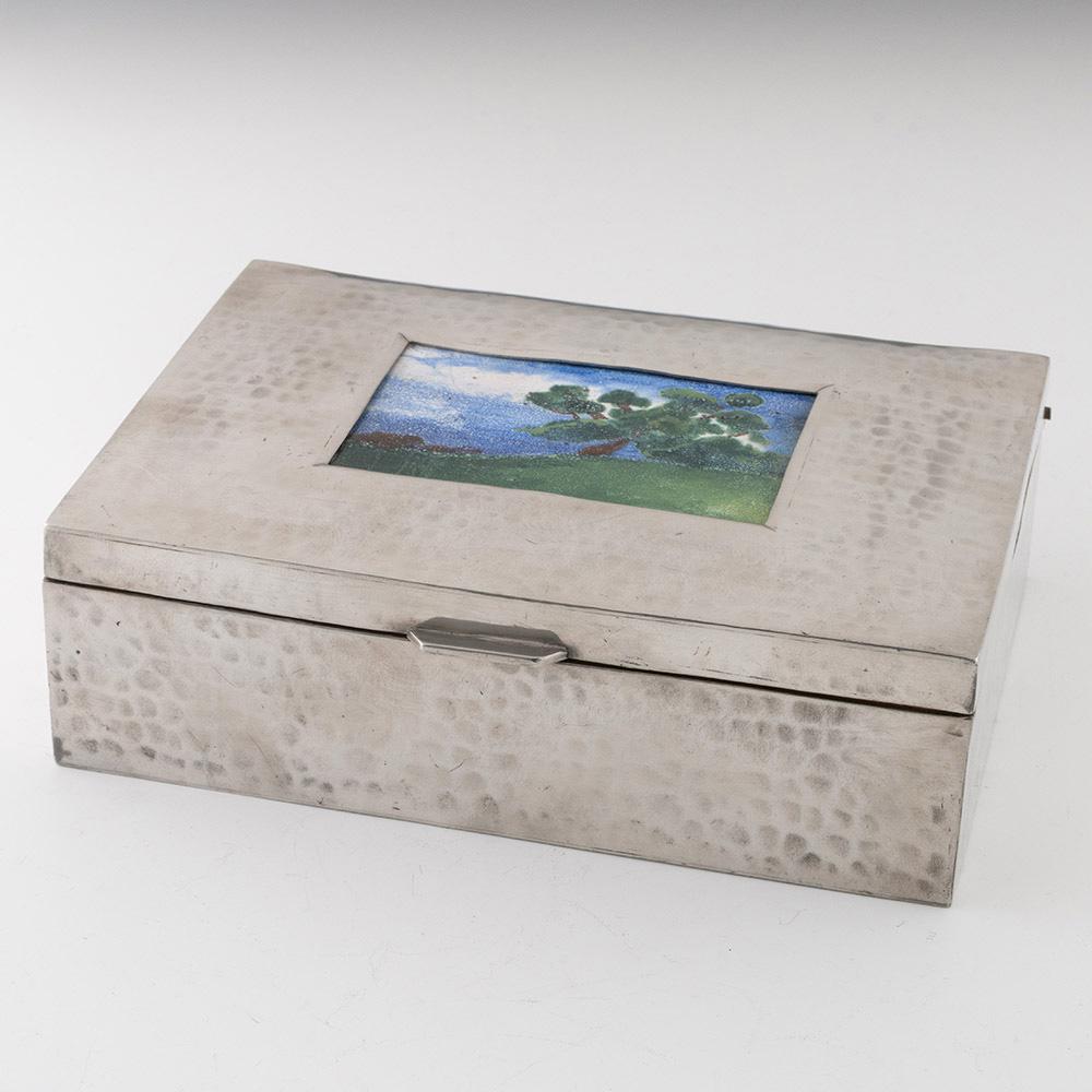 Encabezamiento : Caja de puros de peltre Sheffield con esmalte
Fecha : c1910
Periodo : Eduardo VII
Origen : Sheffield, Yorkshire, Inglaterra
Decoración : Caja martillada (martele) con paisaje esmaltado incrustado. Interior forrado de cedro.
Tamaño :