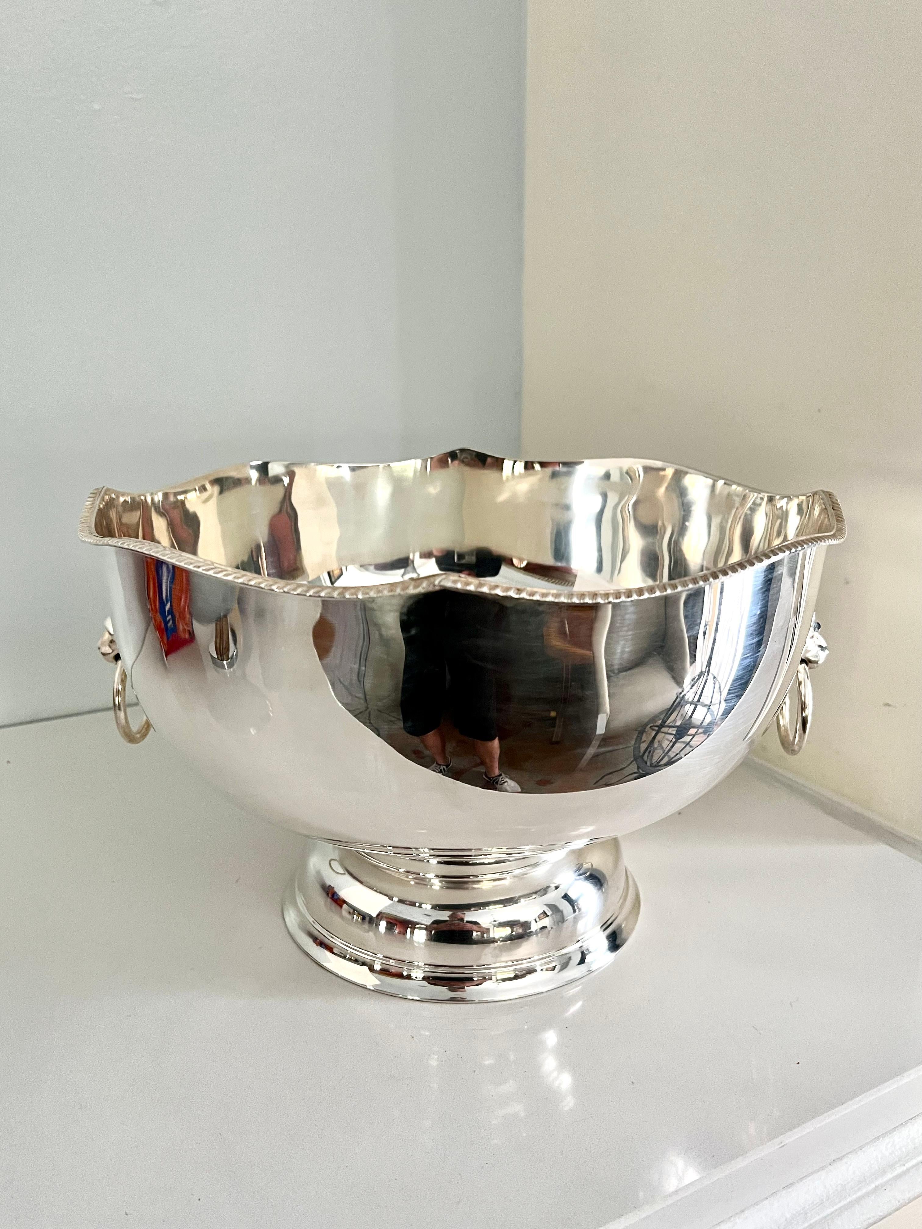 A wonderful English silver plate punch or ice bowl in the style of Sheffield - useful as a decorative piece, a serving piece or even Jardiniere. in very good condition, polished with a detail scallop style edging and a pair of lion heads for handles