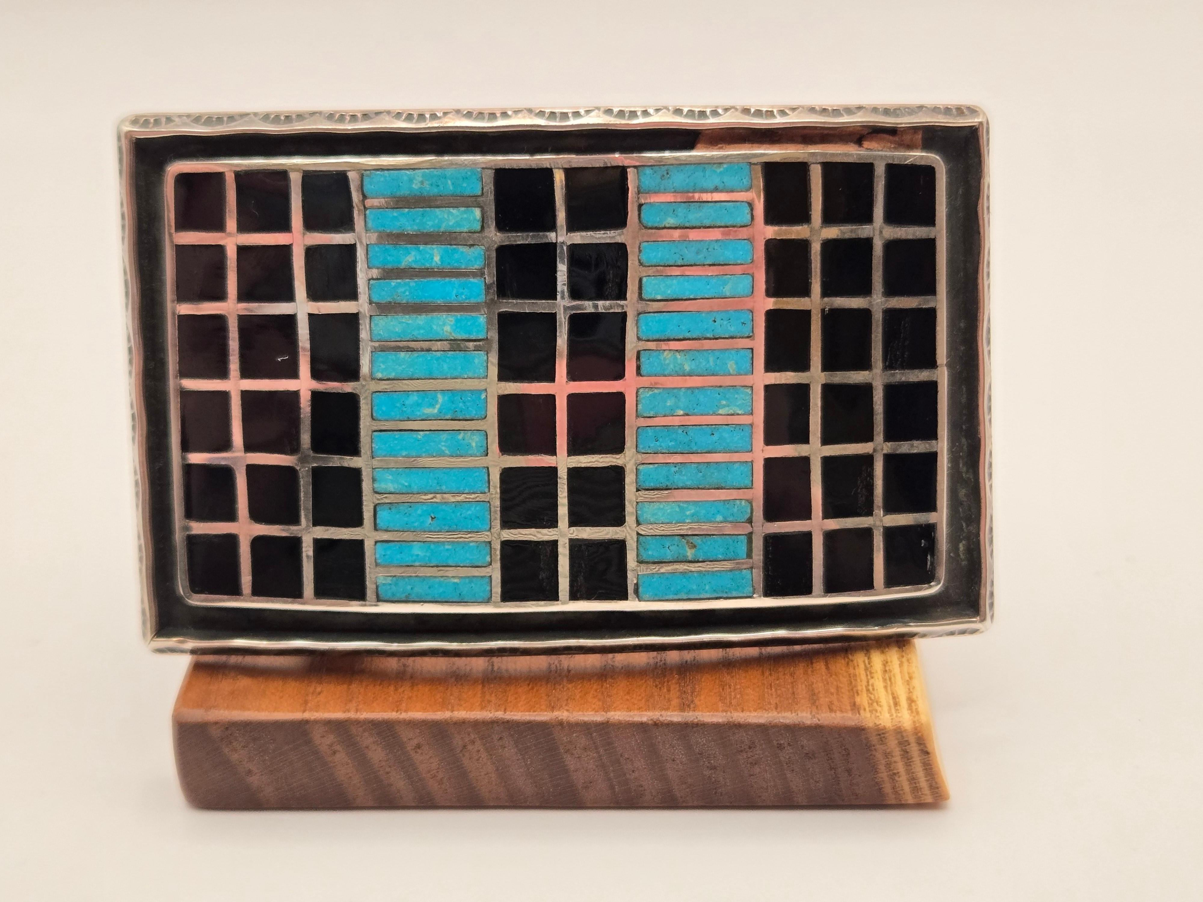 Fibbia da cintura Sheldon & Nancy Zuni New Mexico in argento, onice e turchese

Fibbia da cintura rettangolare in argento sterling con finiture smerlate e martellate e pietre intarsiate di onice e turchese in un motivo quadrato e rettangolare.