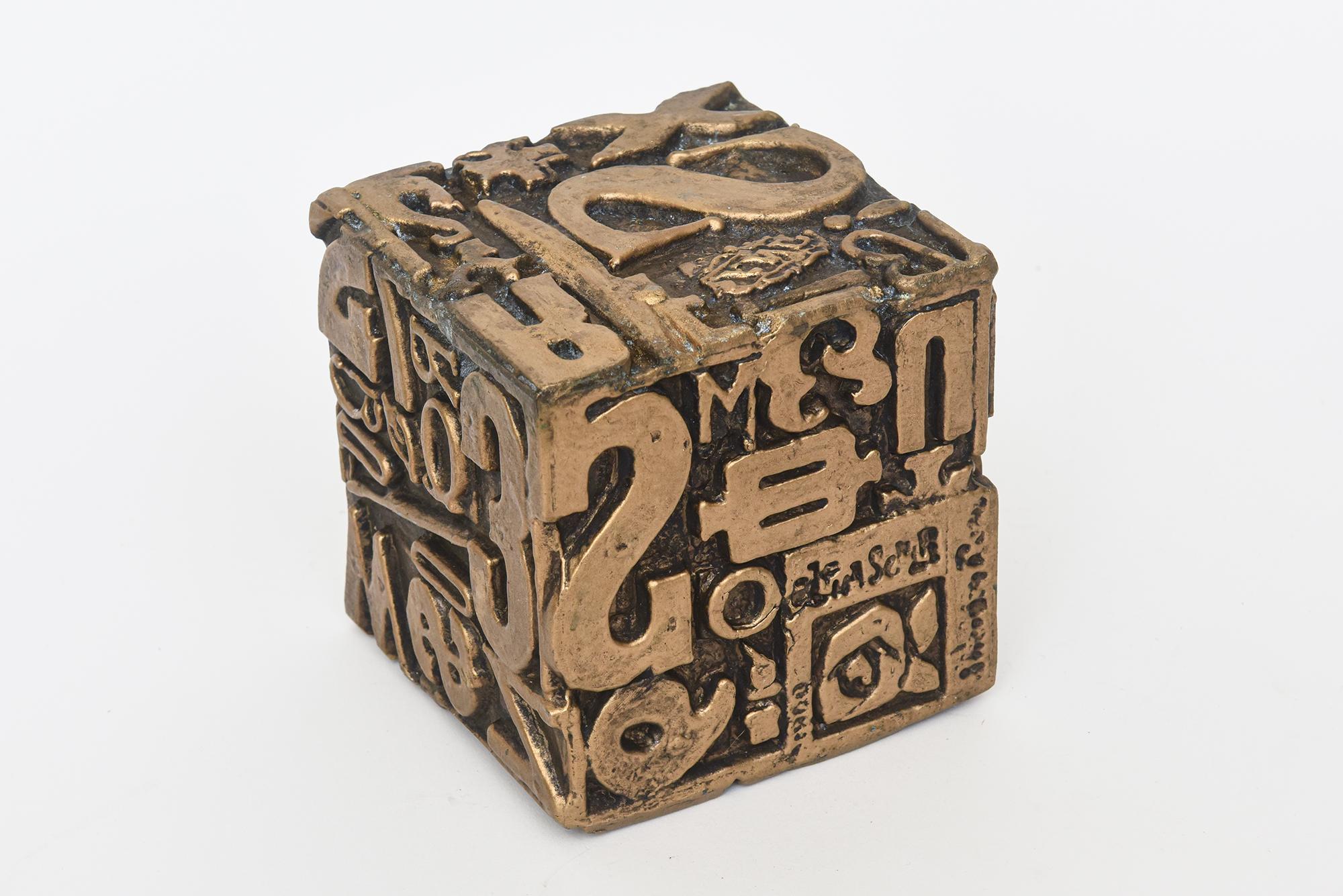 This interesting alpha cube abstract sculpture by Sheldon Rose is a mixed media comprised of polychrome metal and paint. It features a medley of faux letterpress symbols, numbers and letters. Each side is different and feasts the eyes. It is a cast