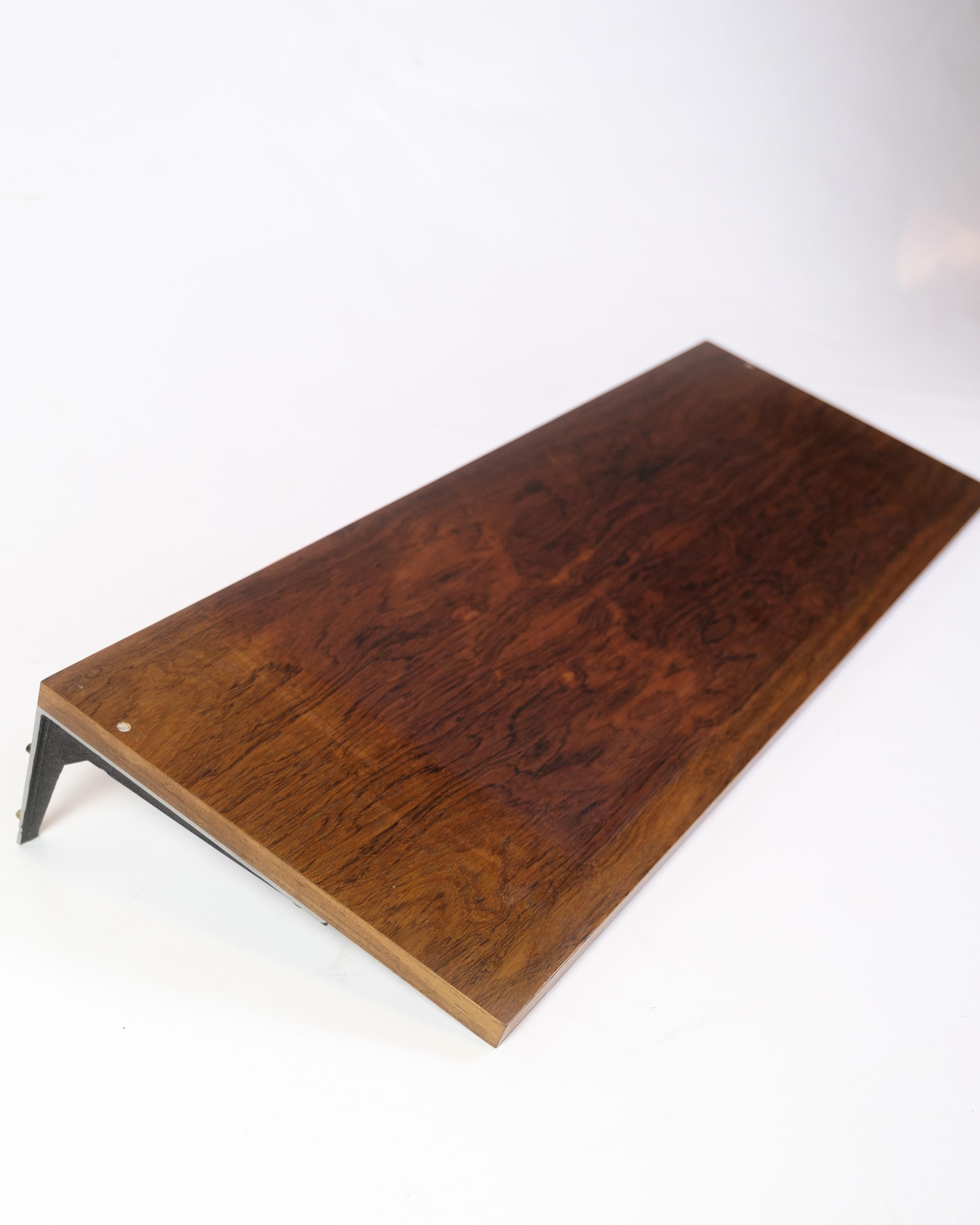 Wall-mounted shelf in rosewood with black lacquered metal suspension, designed by Albert Hansen as part of the Model Excellent series from the 1960s. The slim shape and beautiful grain patterns make the shelf ideal for smaller displays, books or