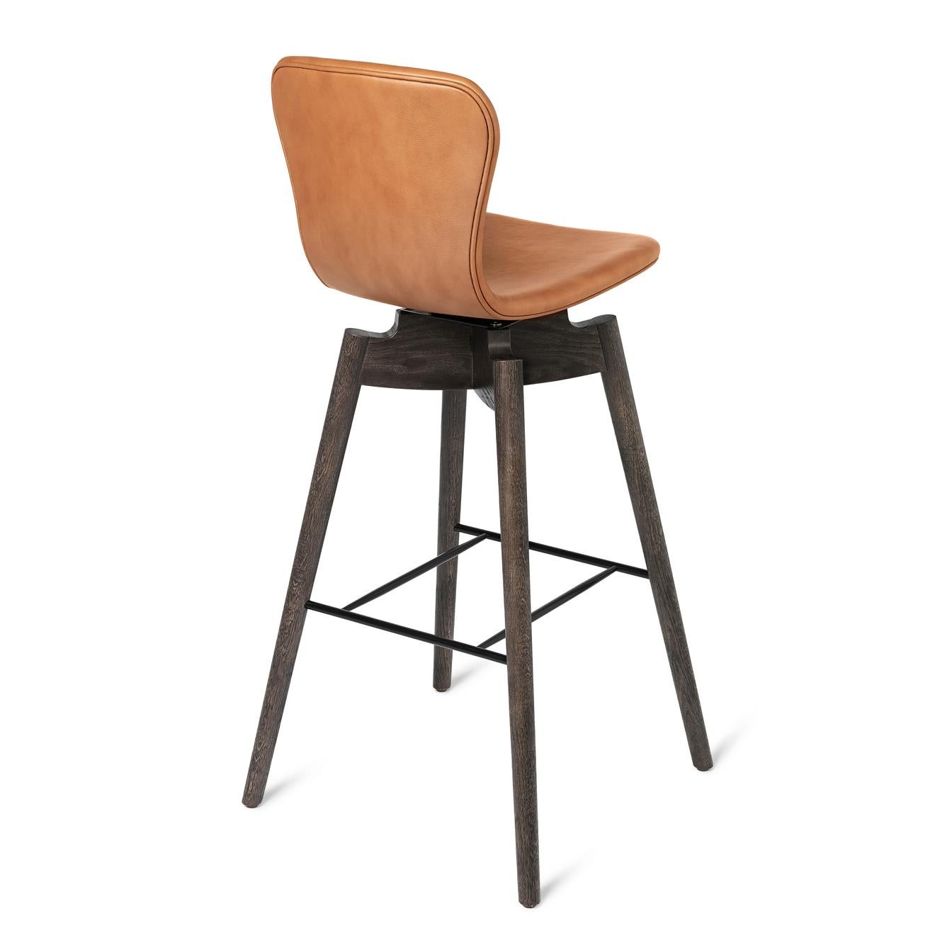 The silhouette of the Shell bar stool is elegant and features long lines in solid oakwood and a soft leather backrest swivel-seat in rich and genuine tones and with clean hand tailored stitches.
Together with the most recognised leather supplier in