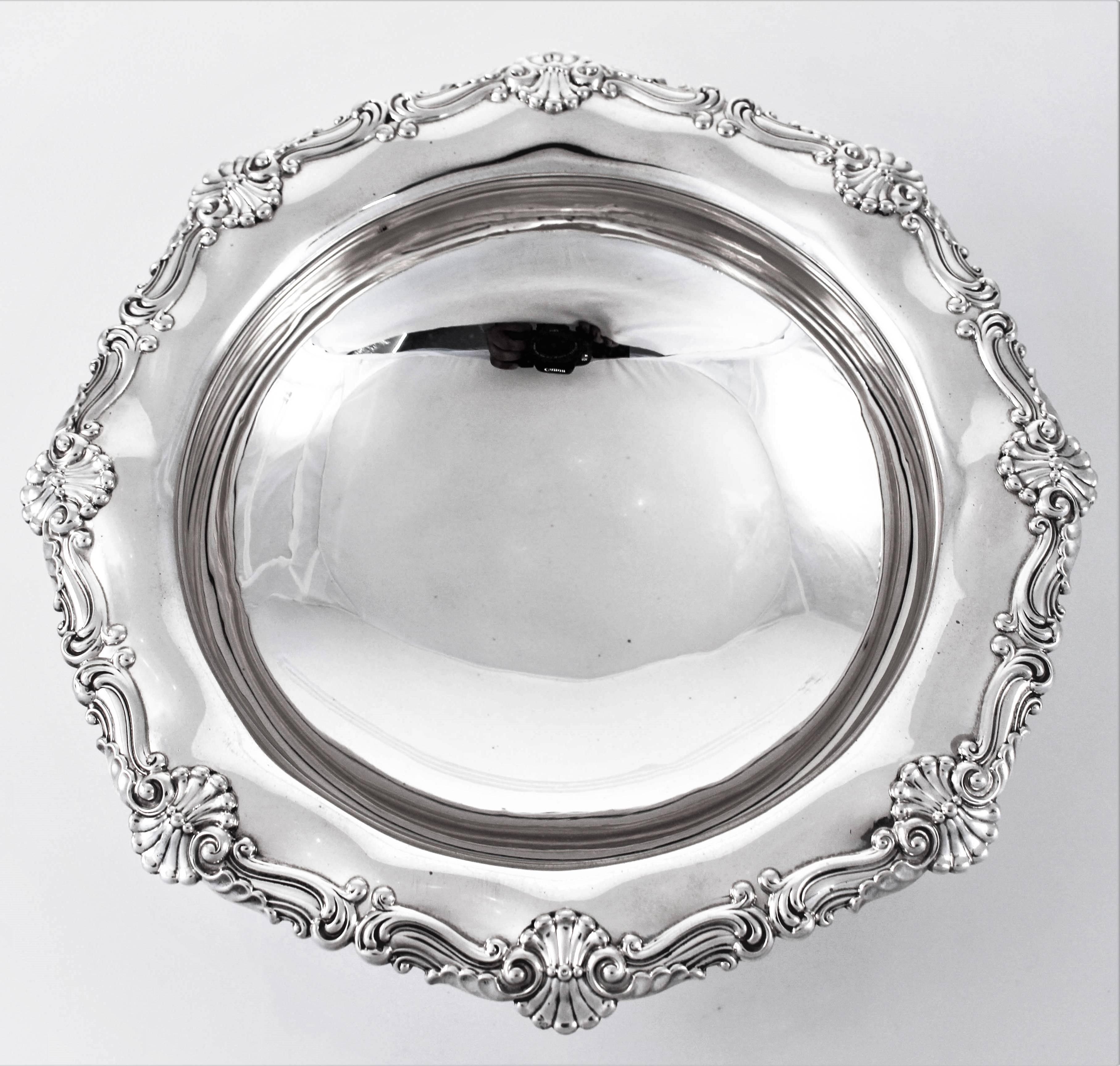 A fine example of antique silver; a one hundred and 18 year old bowl. It has a scalloped rim and matching base. There are shells and a swirl-like design that makes this bowl look important. It also has a nice curvy shape to it. The base is not