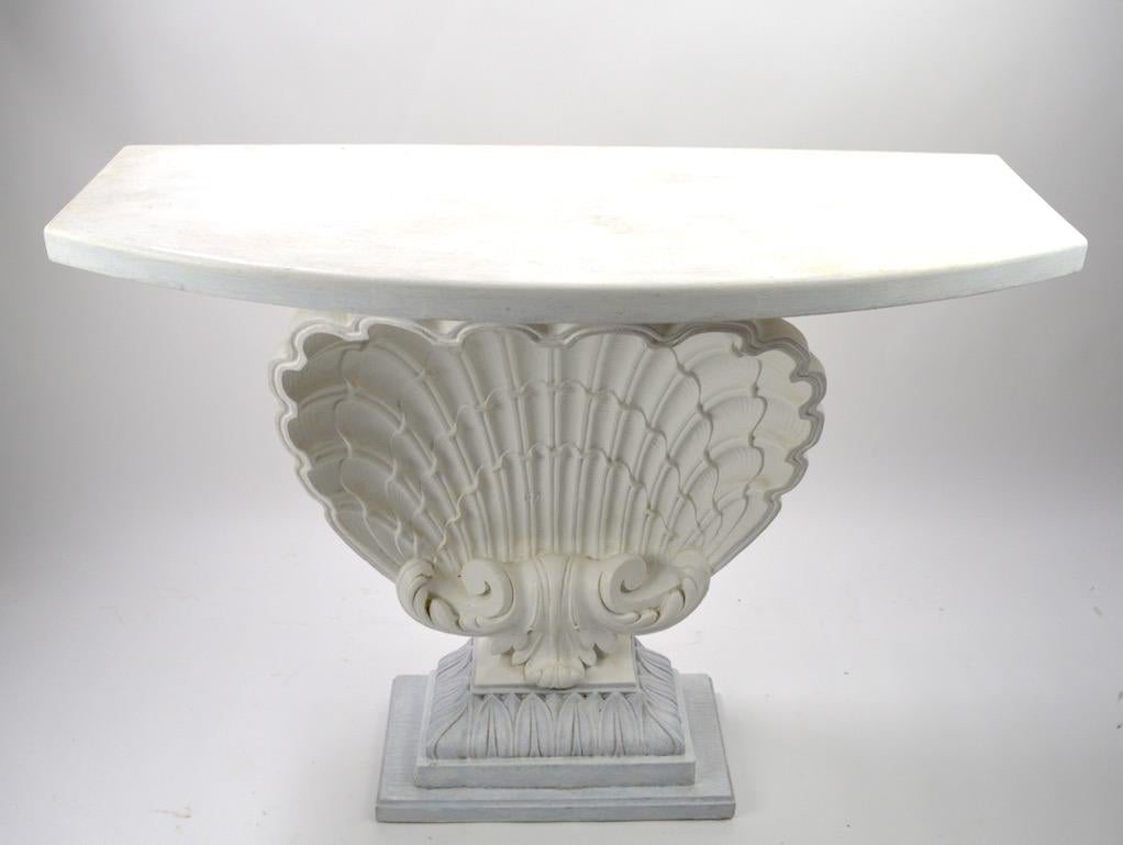 Decorative shell console by Grosfeld House having a cast plaster shell body, with a semi circular top. all mounted on a classical plinth base. Great original condition, showing only light cosmetic wear, normal, and consistent with age. This example