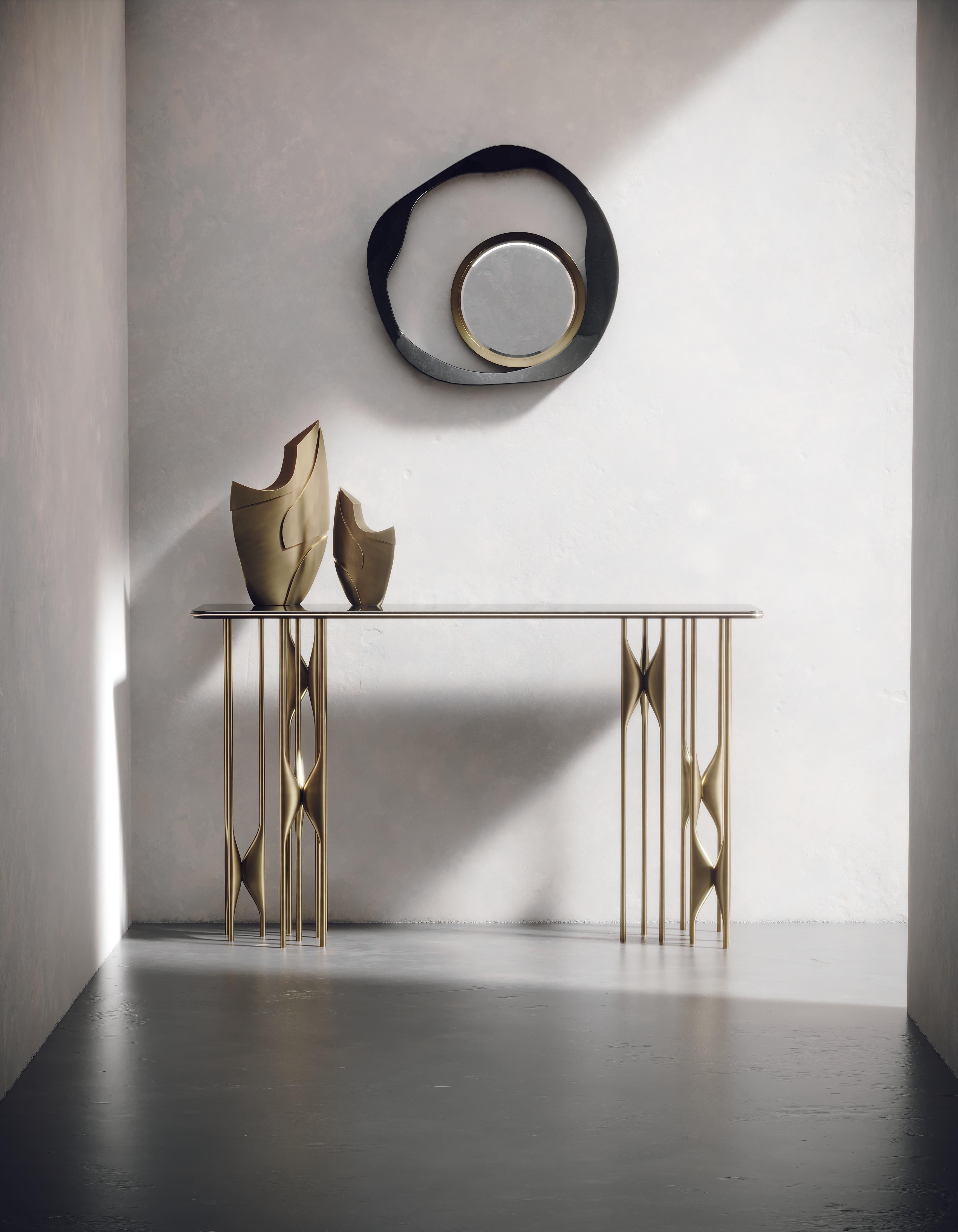 The Plumeria Console by Kifu Paris is a dramatic and sculptural piece. The black pen shell inlaid top sits on clusters of bronze-patina brass legs that are conceptually inspired by bird feathers floating on top of a lake. The border of the top is