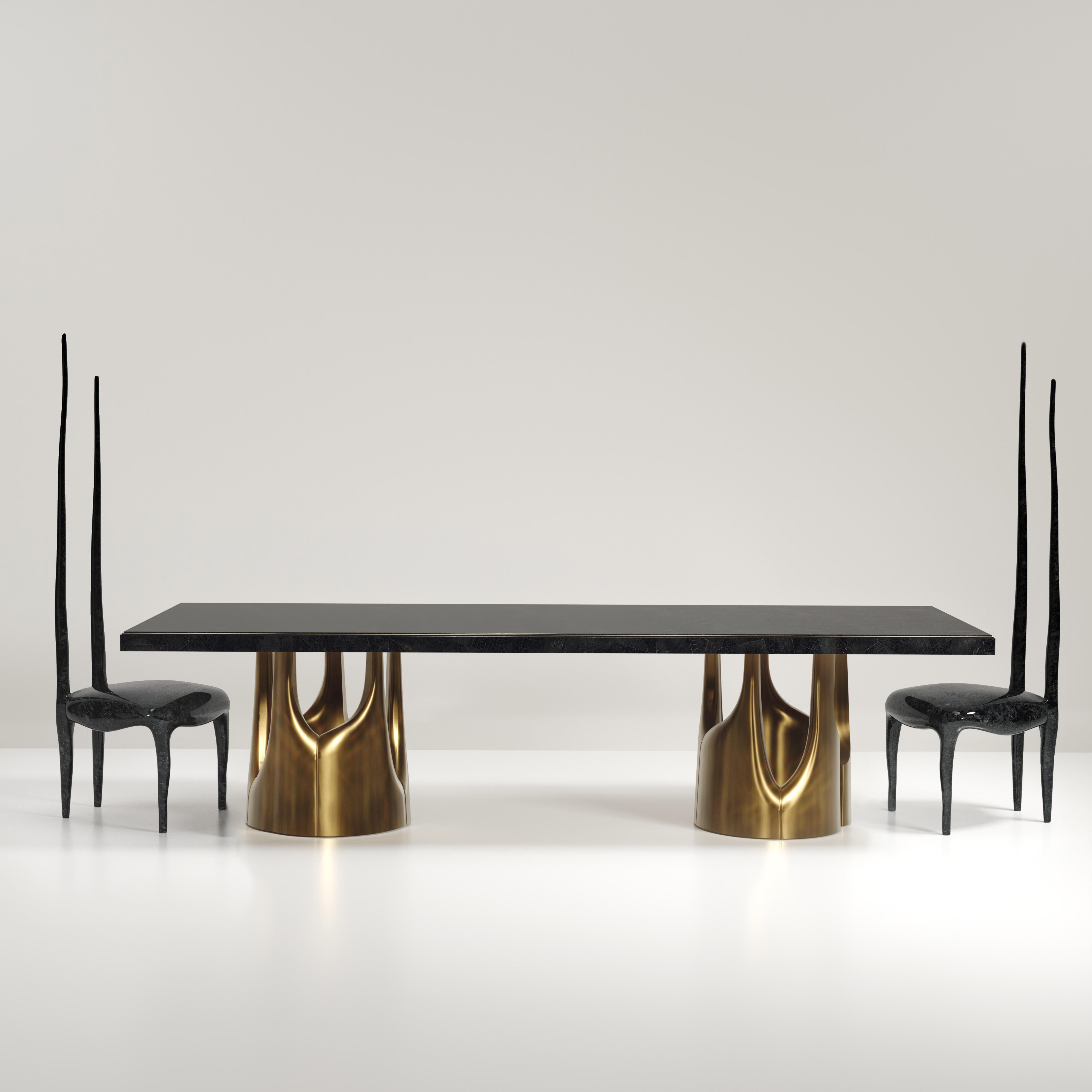 The Triptych I dining table by R&Y Augousti is a stunning multi-faceted sculptural piece. The beautiful hand craved details on the bronze-patina base demonstrate the incredible artisan work of Augousti. The top is inlaid in black pen shell.