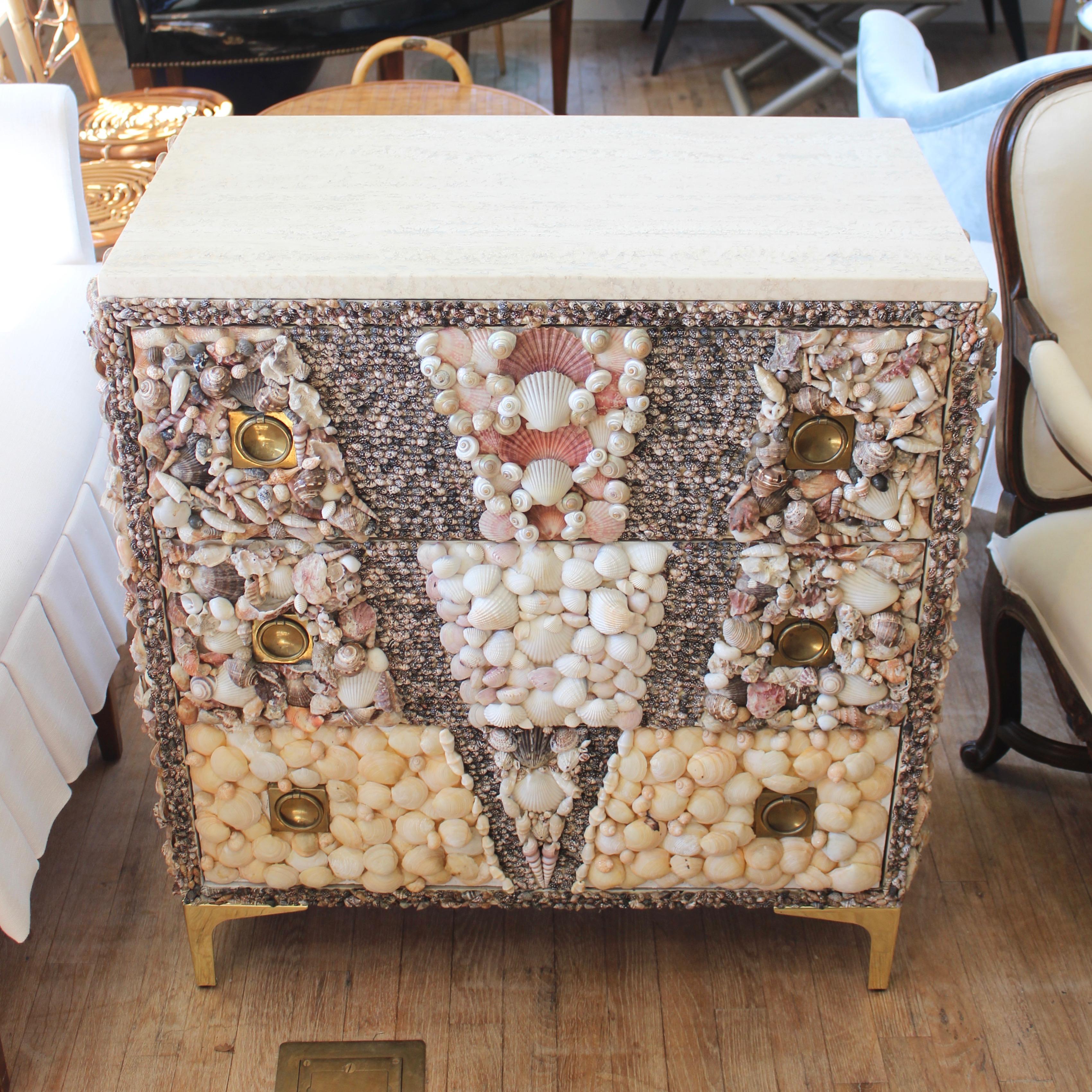 Campaign style chest covered in shells with a honed travertine top and brass legs.