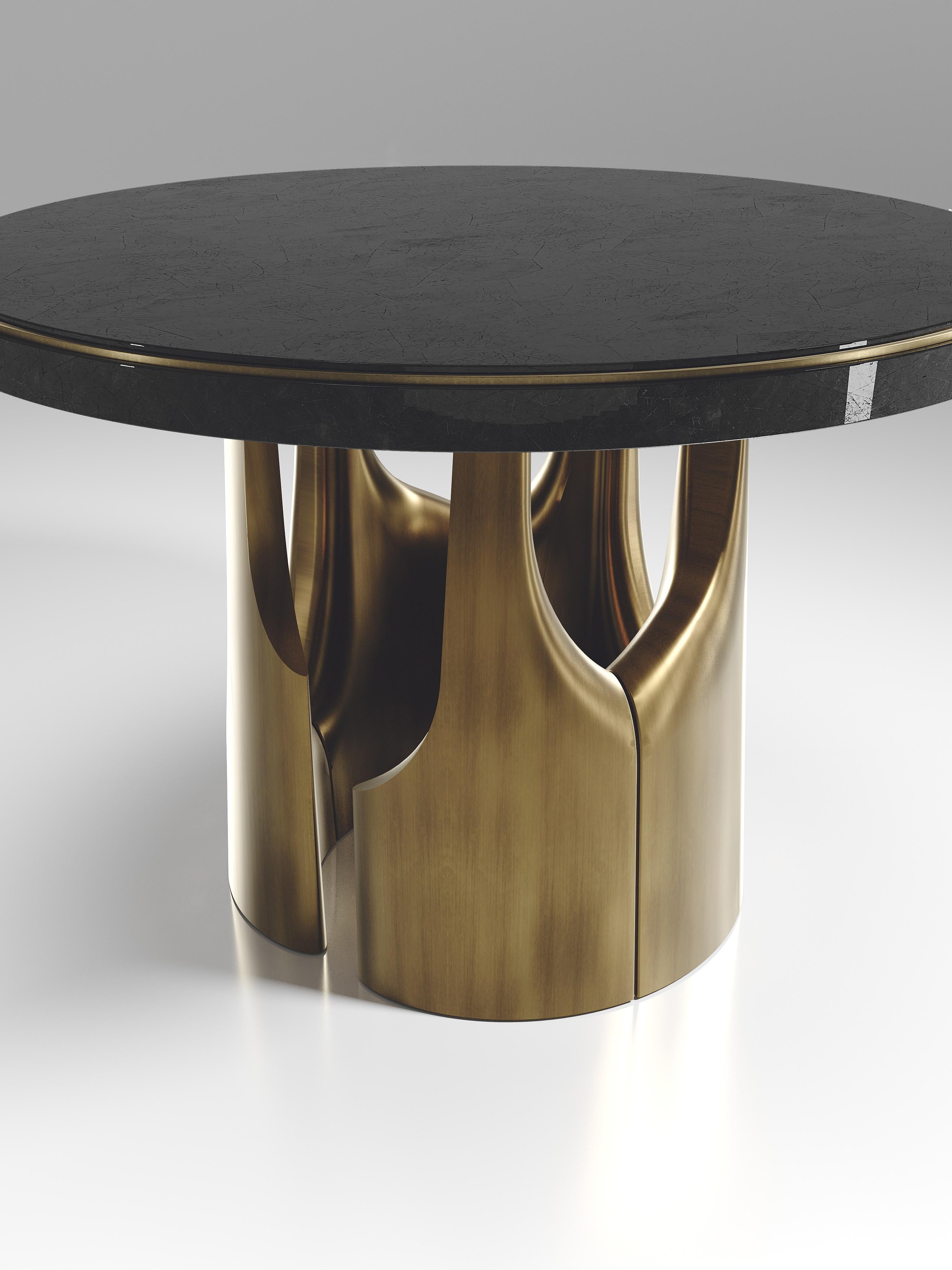 The triptych breakfast table by R&Y Augousti is a stunning multi-faceted sculptural piece. The beautiful hand craved details on the bronze-patina base demonstrate the incredible artisan work of Augousti. The top is inlaid in black shell. Available