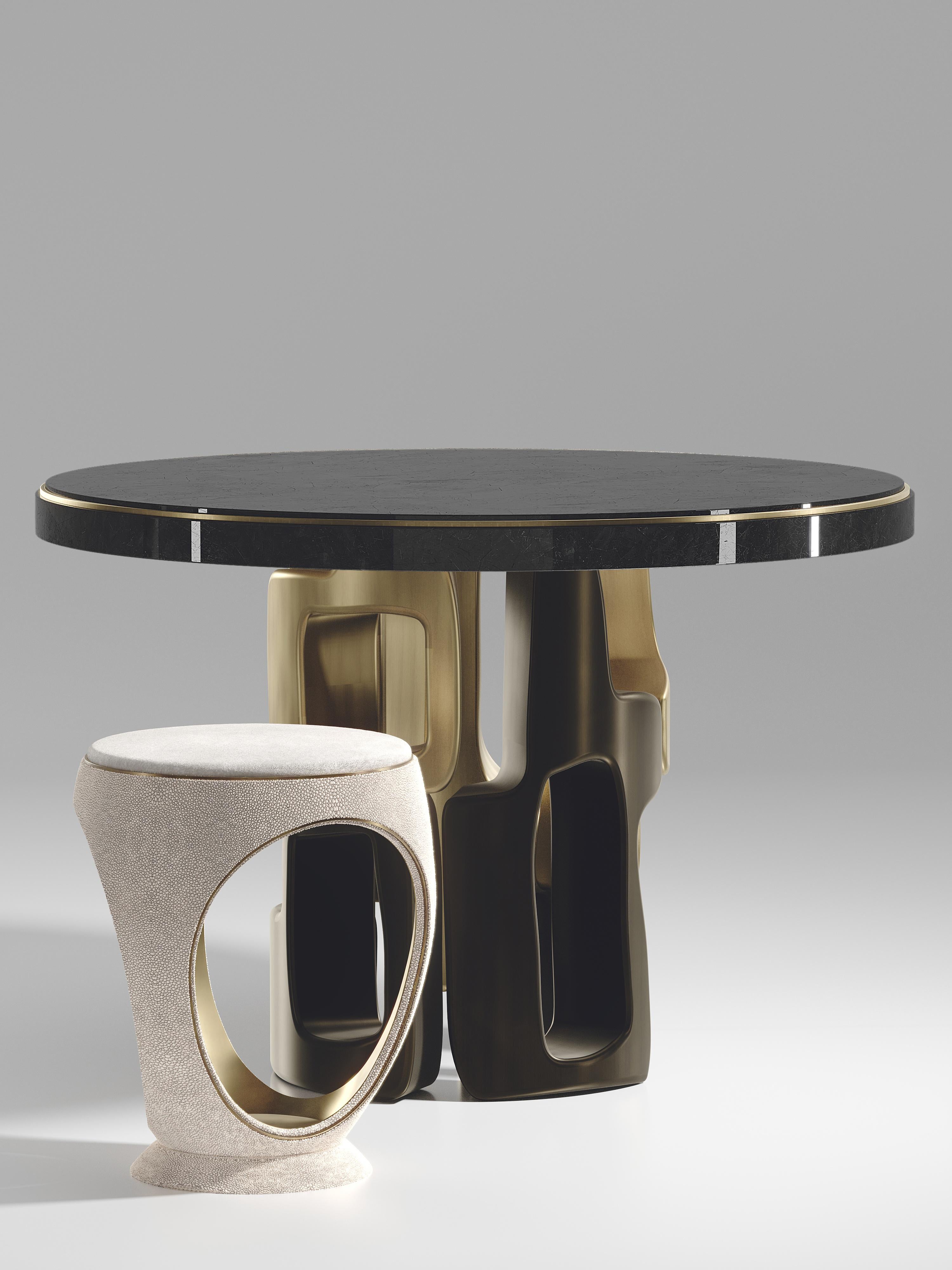 The Apoli breakfast table by Kifu Paris is both dramatic and organic its unique design. The black pen shell inlaid top sits on an ethereal geometric and sculptural bronze-patina brass base. This piece is designed by Kifu Augousti the daughter of Ria