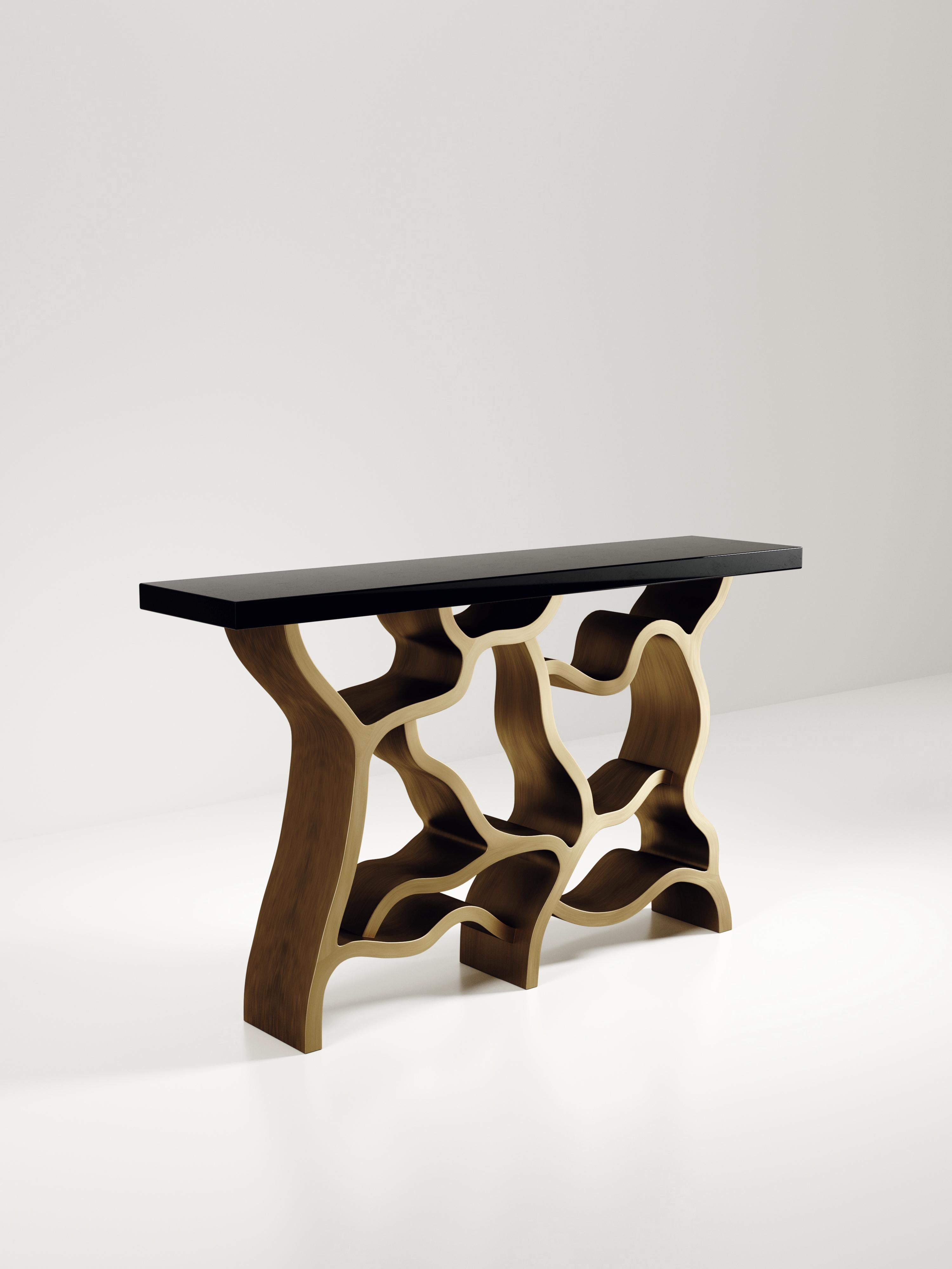 La table console Leaf de Kifu Paris est une pièce spectaculaire et organique. Le plateau rectangulaire incrusté de coquilles de stylo noires repose sur un socle en laiton bronze-patine qui évoque des branches entrelacées. Cette pièce a été conçue