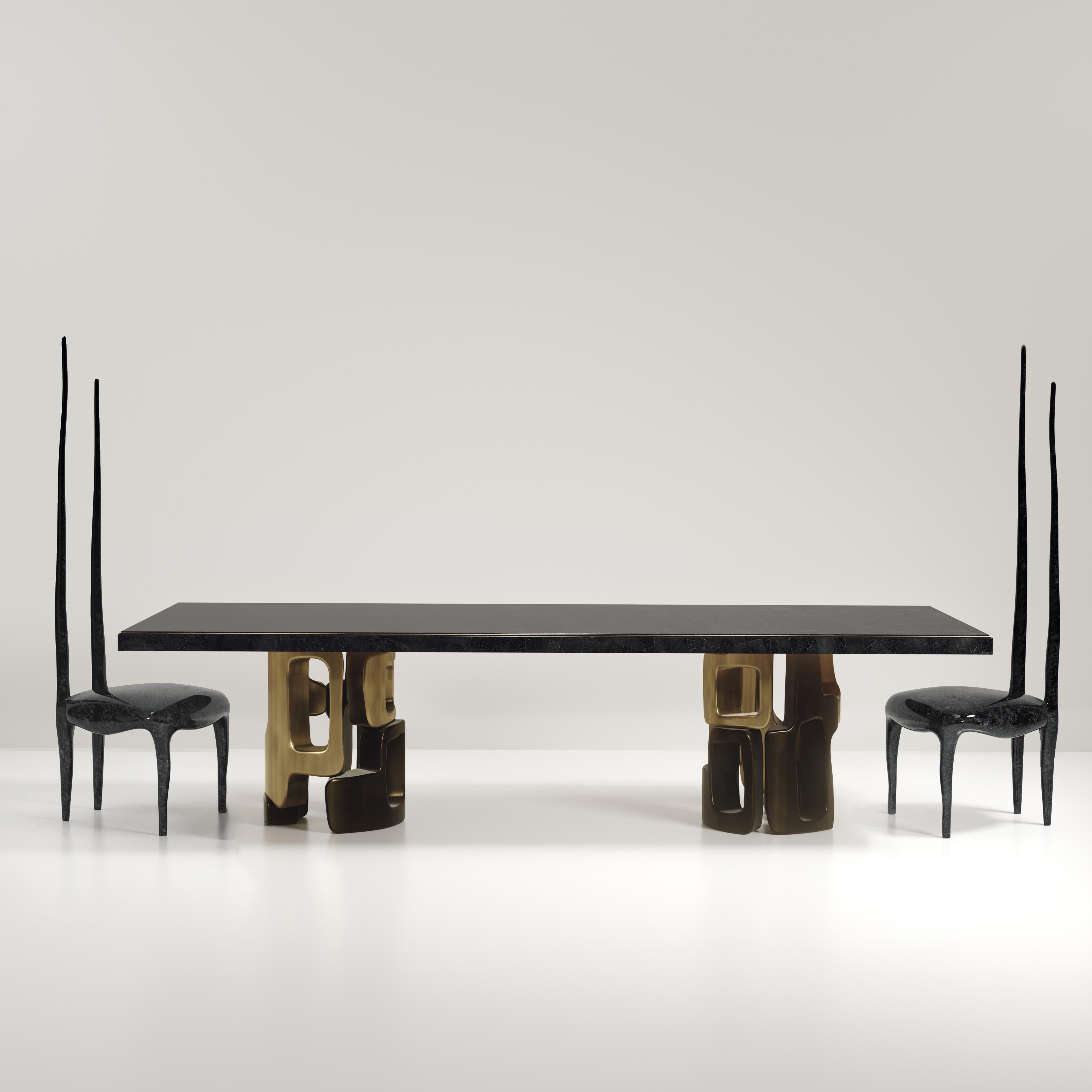 The Apoli I dining table by Kifu Paris is both dramatic and organic its unique design. The black pen shell inlaid top sits on a pair of geometric and sculptural bronze-patina brass bases. This piece is designed by Kifu Augousti the daughter of Ria
