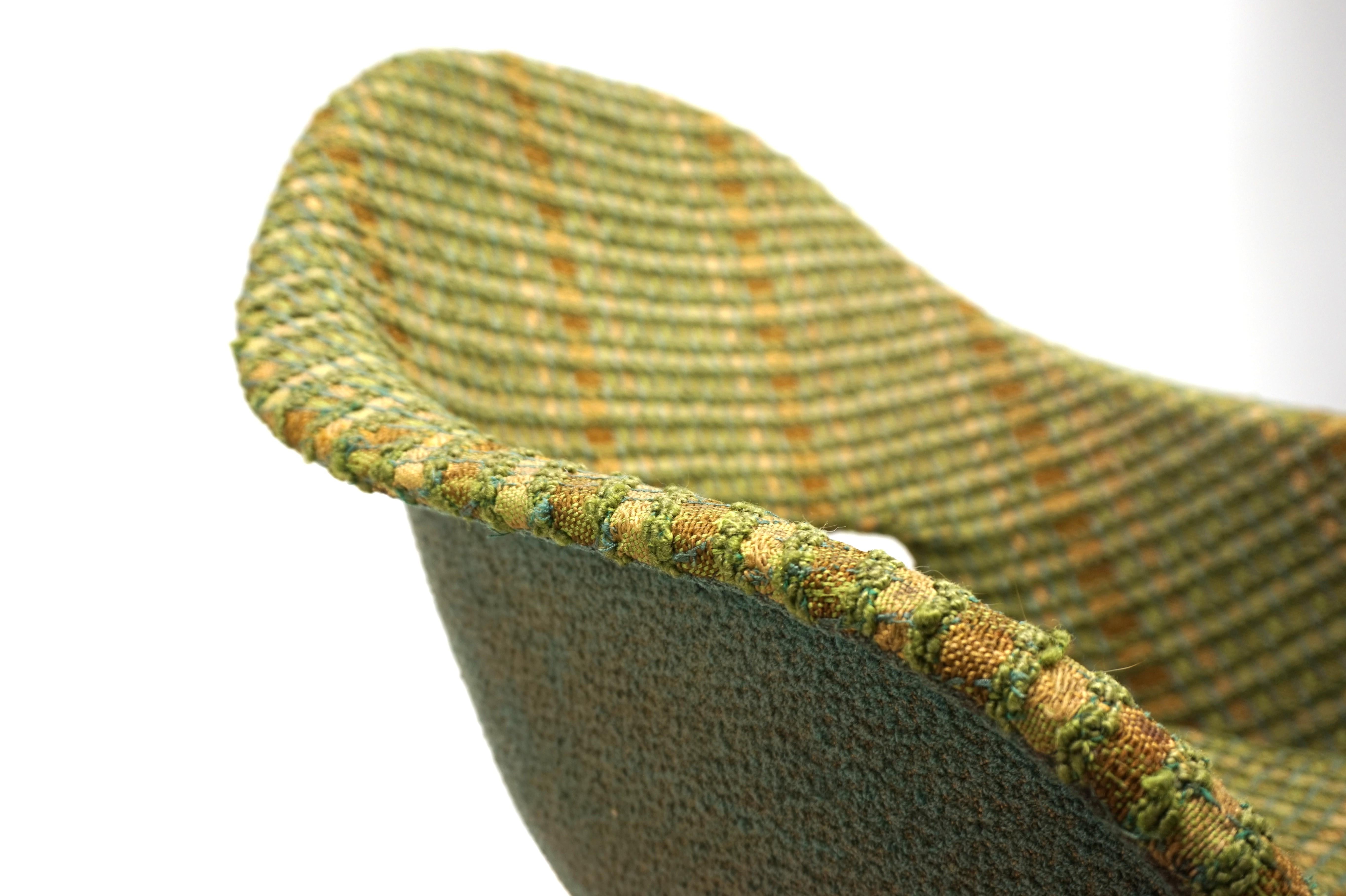 A shell armchair by Navratil with the original upholstery in stunning colors and patina. The fabric upholstery in various shades of green with brown stripes shows slight signs of wear but has lost none of its appeal. The back of the armchair