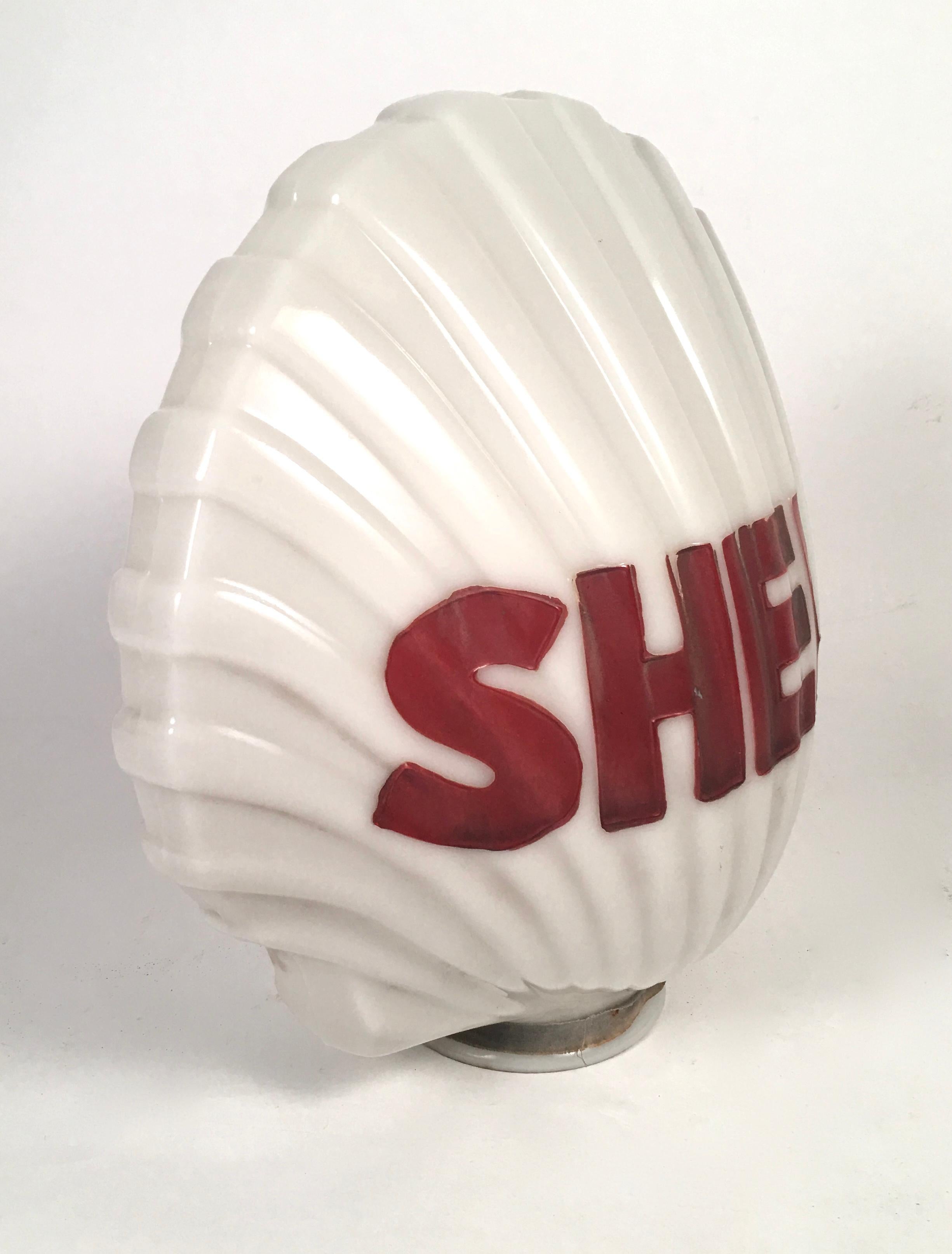 A Shell Oil Company molded scallop shell-form milk glass figural globe which would have been an illuminated light shade at the gas pump, with the word SHELL painted in large red letters American, circa 1930s.


