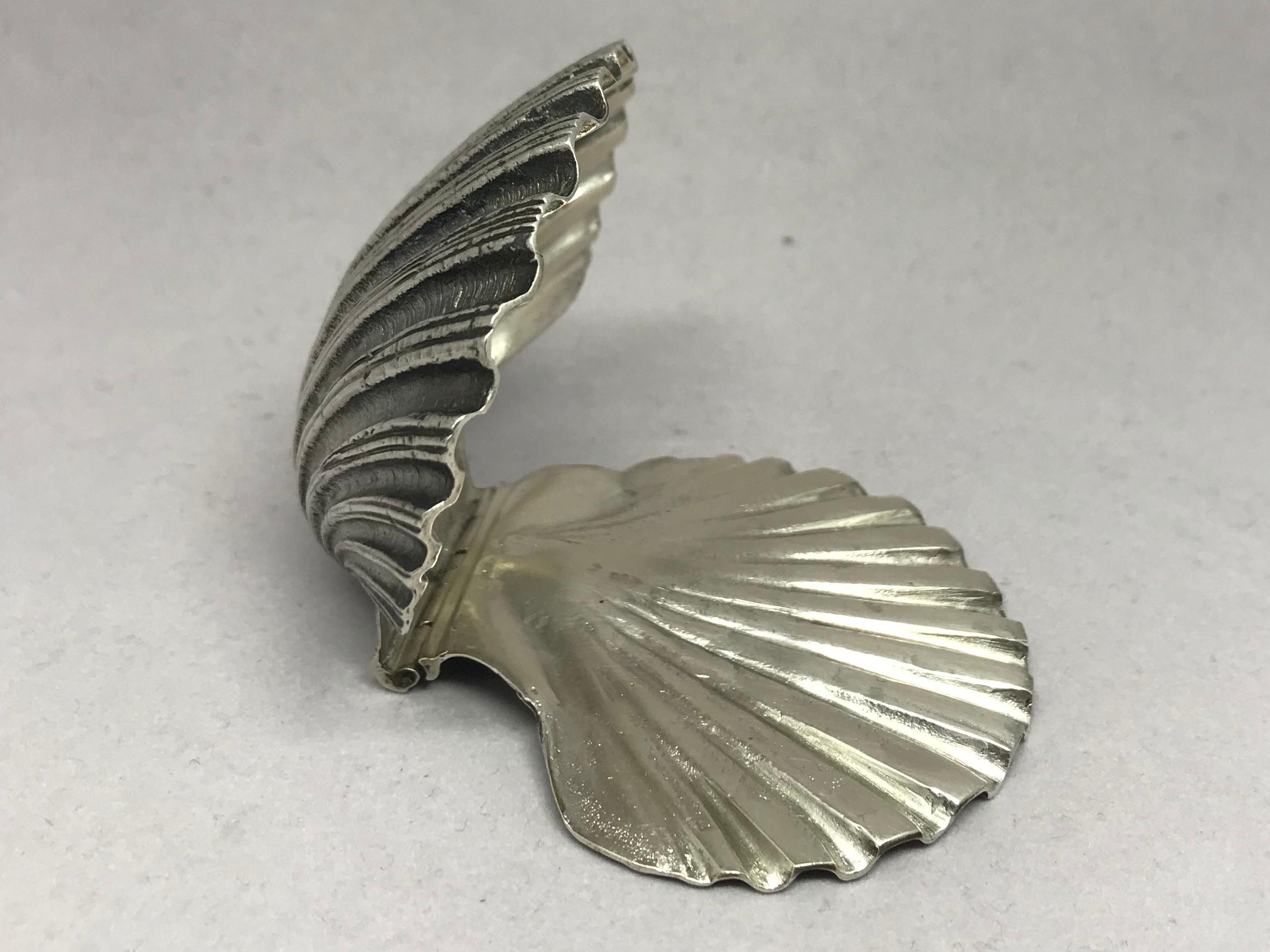 Shell paper clamp in Italian sterling silver. Finely wrought hinged silver shell desk accessory for holding current papers elegantly in place with Italian hallmarks. Italy, circa 1930.
Dimensions: 3