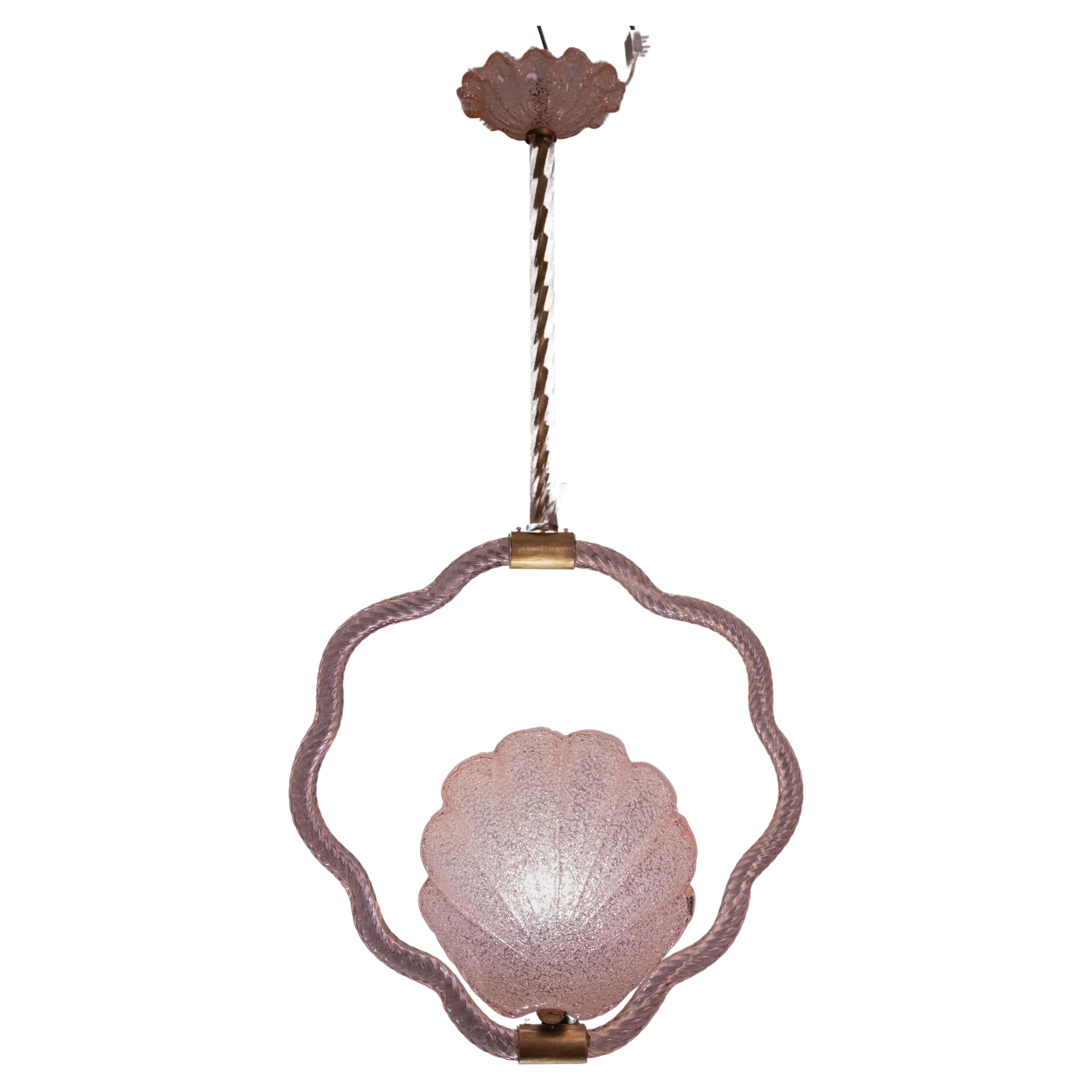 Superbe lustre de Murano réalisé par l'artiste Barovier&Toso avec un verre rose rare.
La suspension se compose de 5 éléments en verre et d'une structure en laiton, en forme de coquillage.
Il permet de monter une lampe européenne standard e27.
Il
