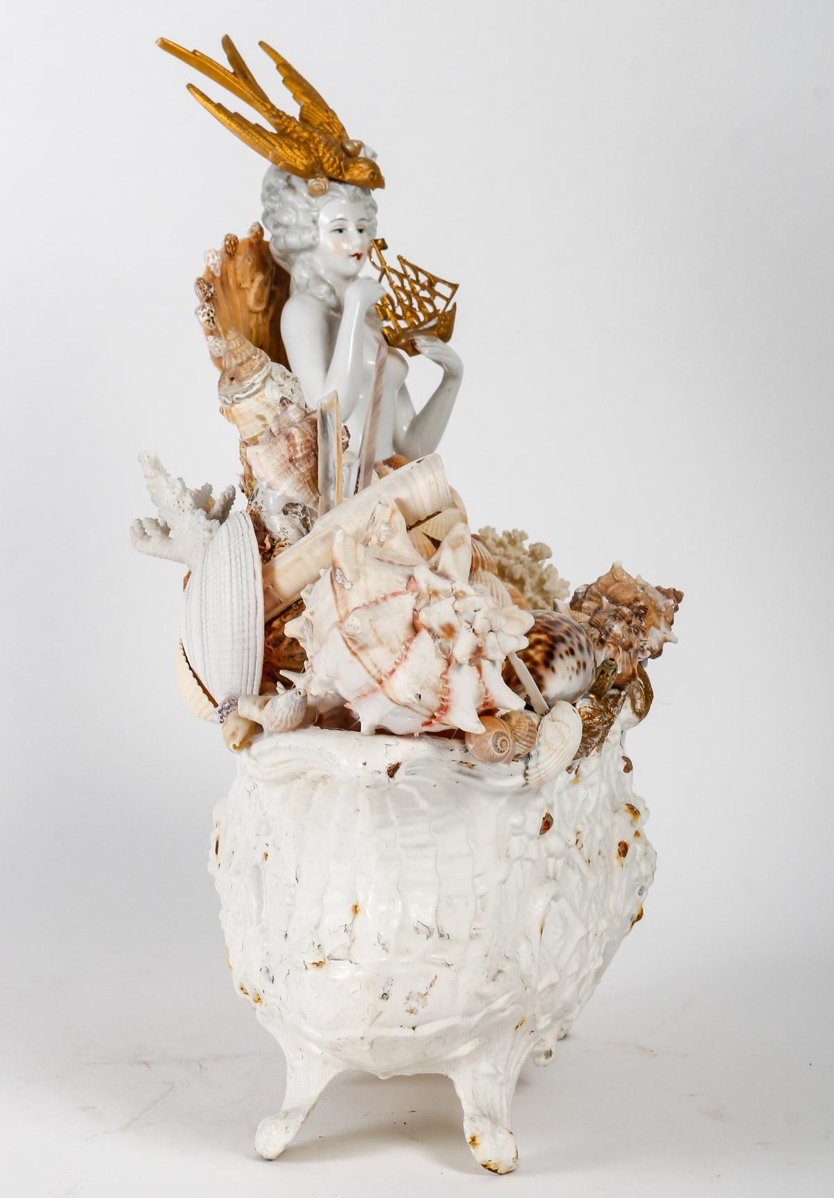 Shell sculpture and planter in cast iron and porcelain.

Sculpture composed of a cast iron planter decorated with shells and a porcelain figure, 20th century.
h: 41cm, l: 45cm, p: 20cm
