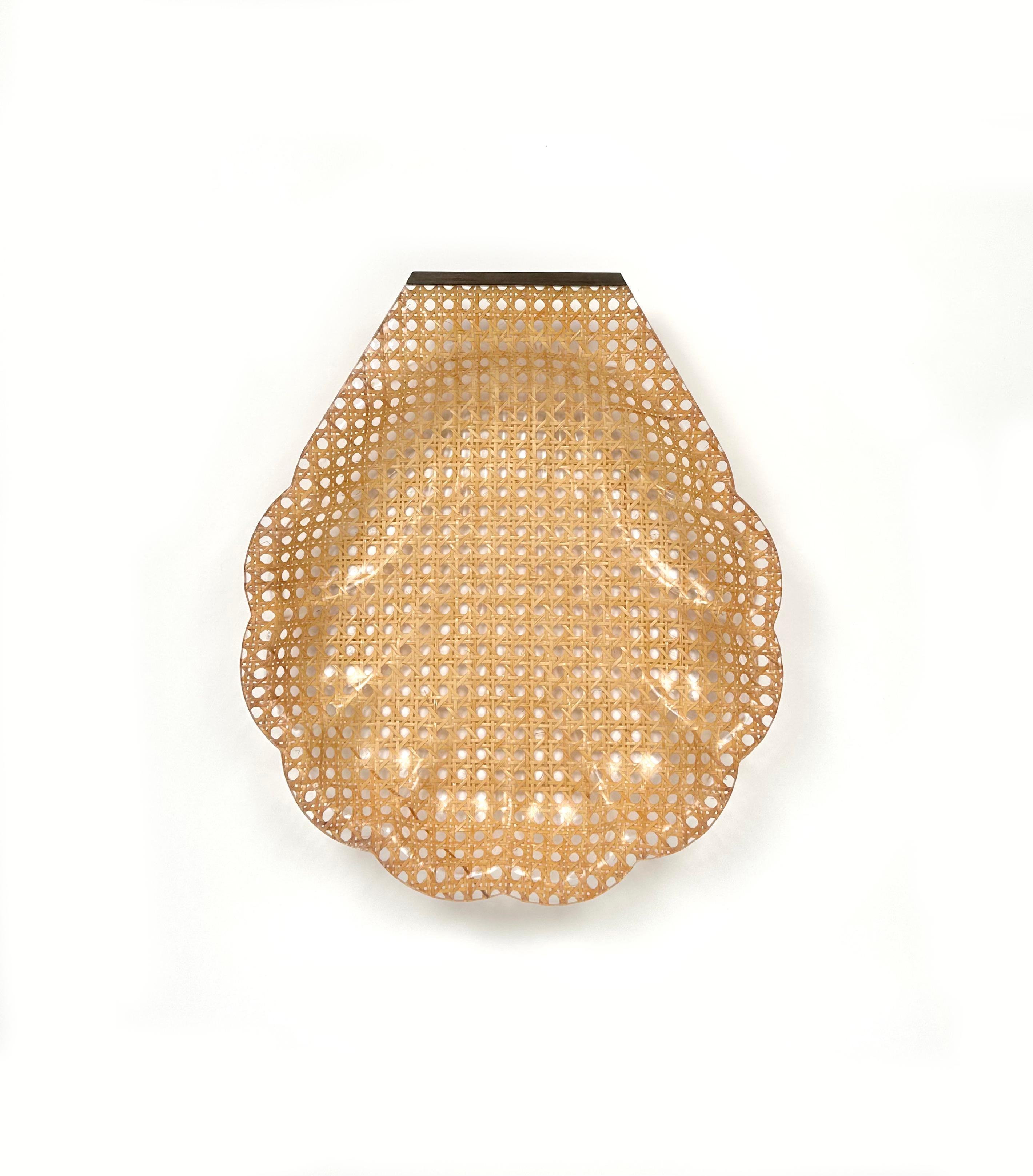 Shell shaped centerpiece / serving tray in lucite, rattan and brass detail in the style of Christian Dior Home.

Made in France in the 1970s.