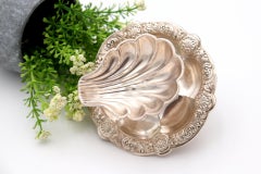 Shell-shaped ring on a ball and raised base with three cut-out feet