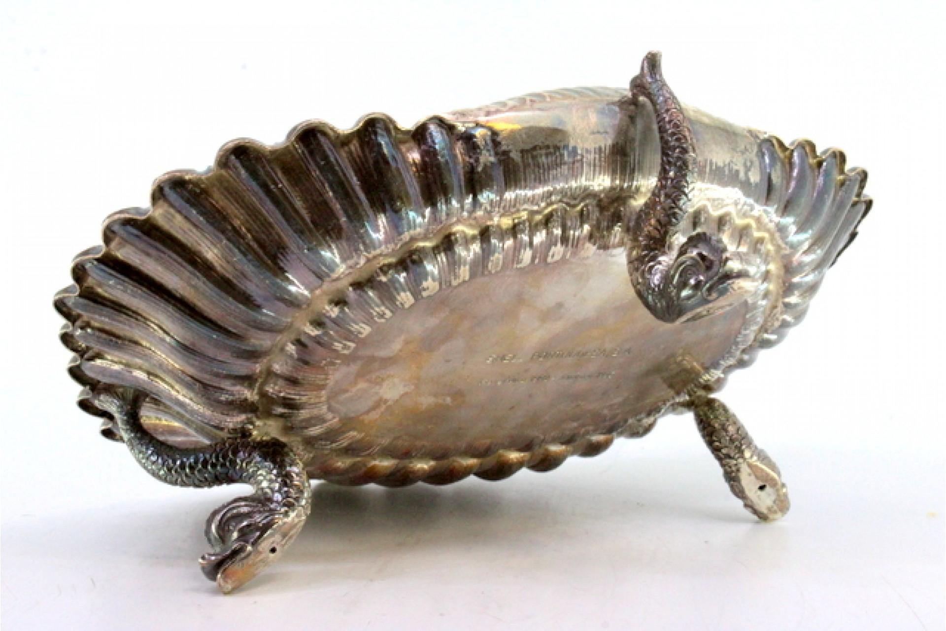 Description: Silver fruit bowl in the shape of a shell with reliefs, resting on three feet in the shape of fish. Metal: Silver. Origin: Portuguese. Mark: open-winged eagle. Weight: 606.51 grams. Dimensions: 26cm x 20.5cm. Content: 925/1000. Assay