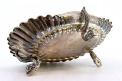 Shell-shaped silver fruit bowl with reliefs and three fish-shaped feet