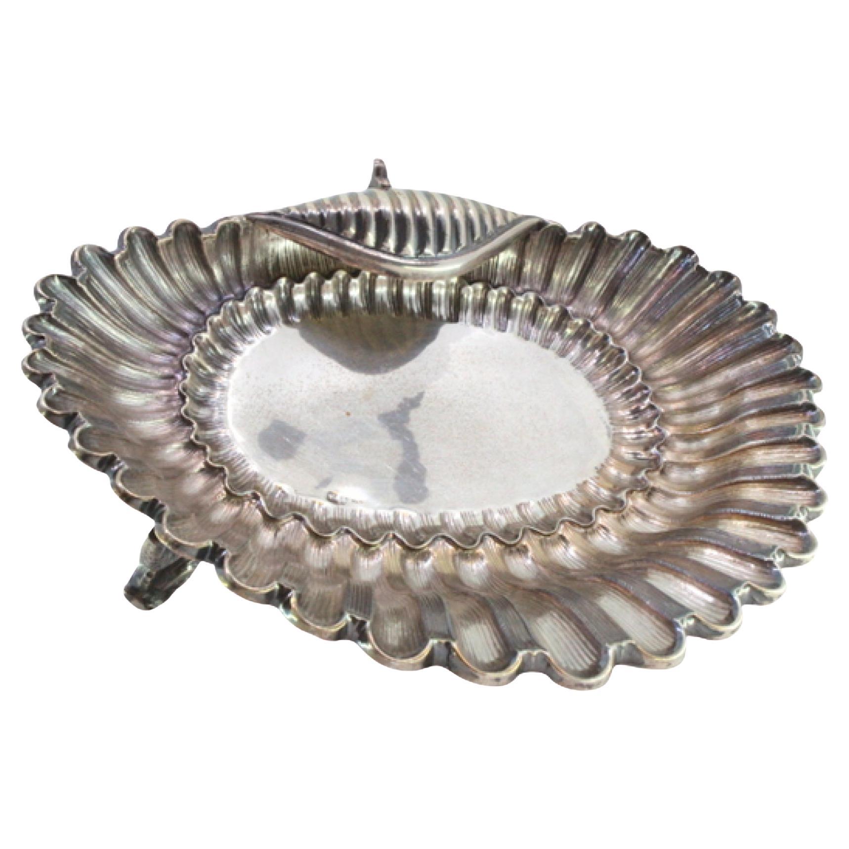 Shell-shaped silver fruit bowl with reliefs and three fish-shaped feet