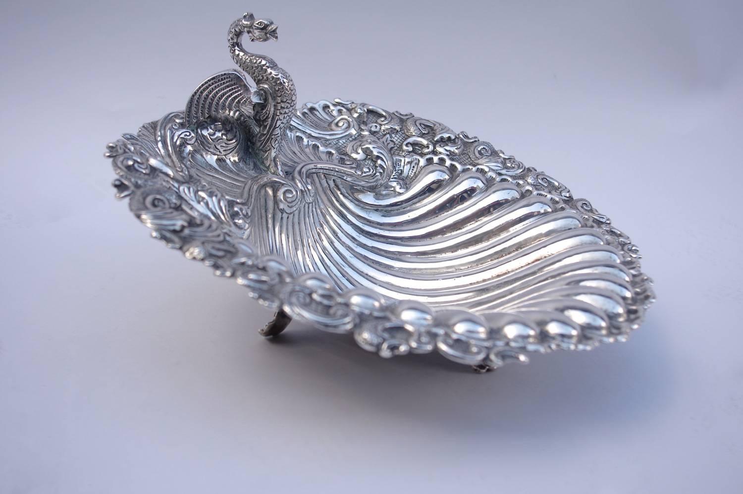 Louis XV style shell-shaped silver plated centerpiece decorated with gadroons, volutes and vegetal interlaces, standing on three small curved legs.
A creature sculpted in the round, probably a phoenix or a basilic, overhangs the central part of the