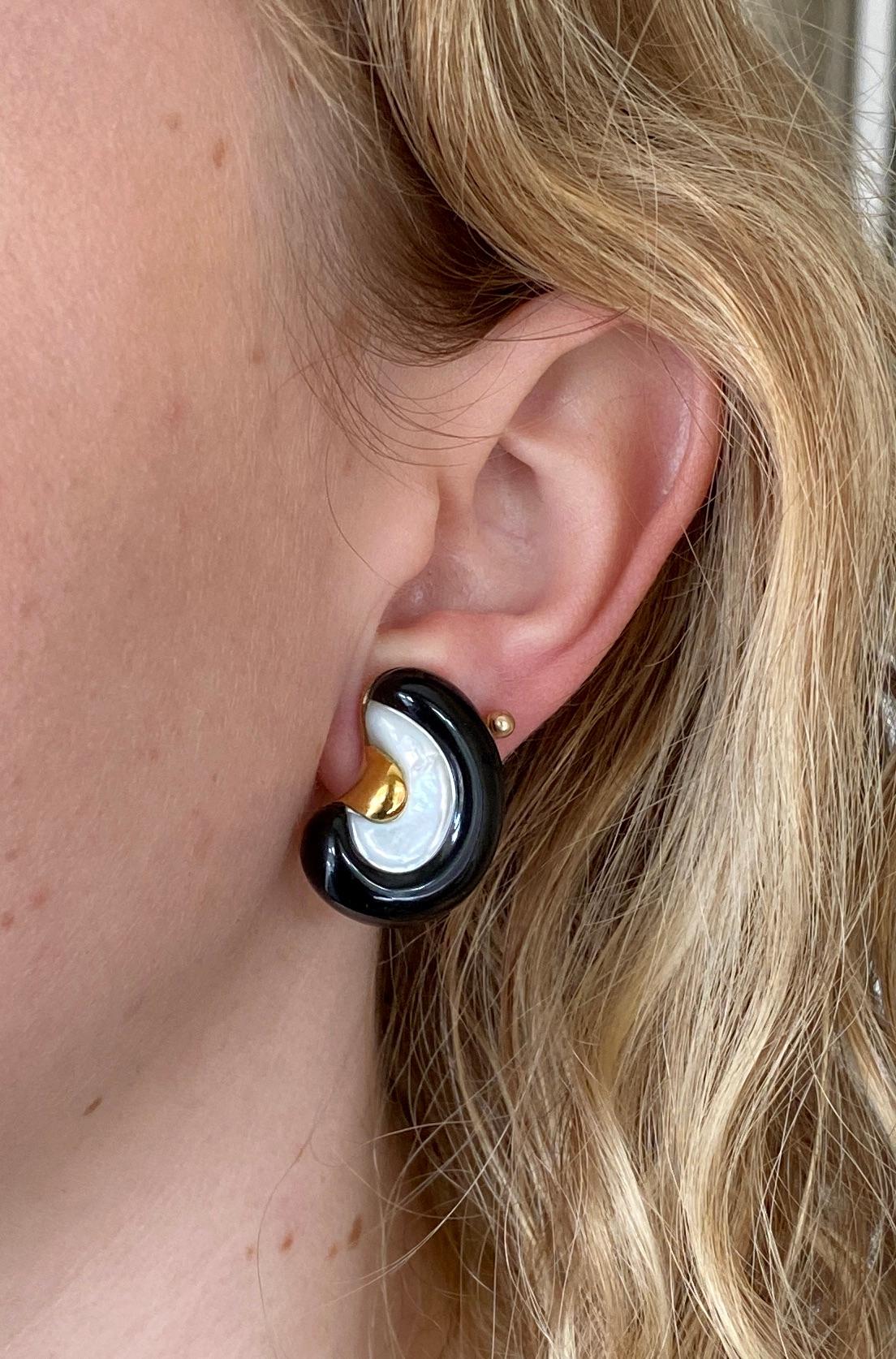 A pair of classic black, white and gold earrings.

The omega-backed earrings feature carved black onyx and white mother-of-pearl set in 14K yellow gold. 

They measure just over an inch (26.3mm) high and together weigh 16 1/2 grams. Each earring is