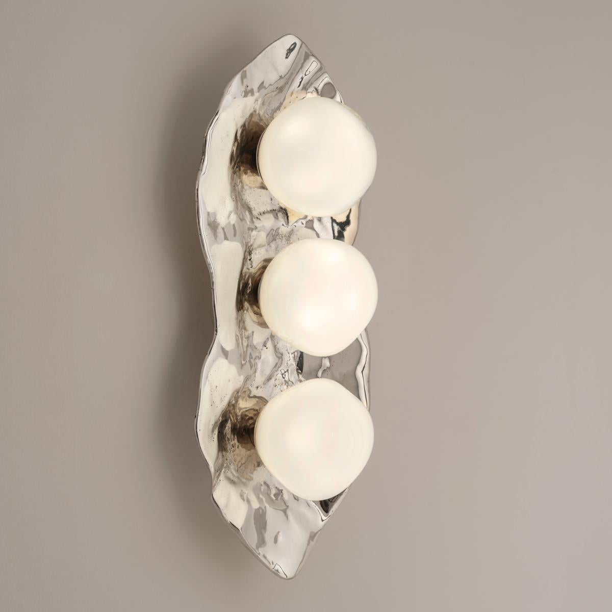 The Shell wall light is forged from brass to create an organic shell nestling three of our handblown Sfera glasses made in Murano.

Shown in the primary images in polished nickel -subsequent pictures show the fixture in other featured
