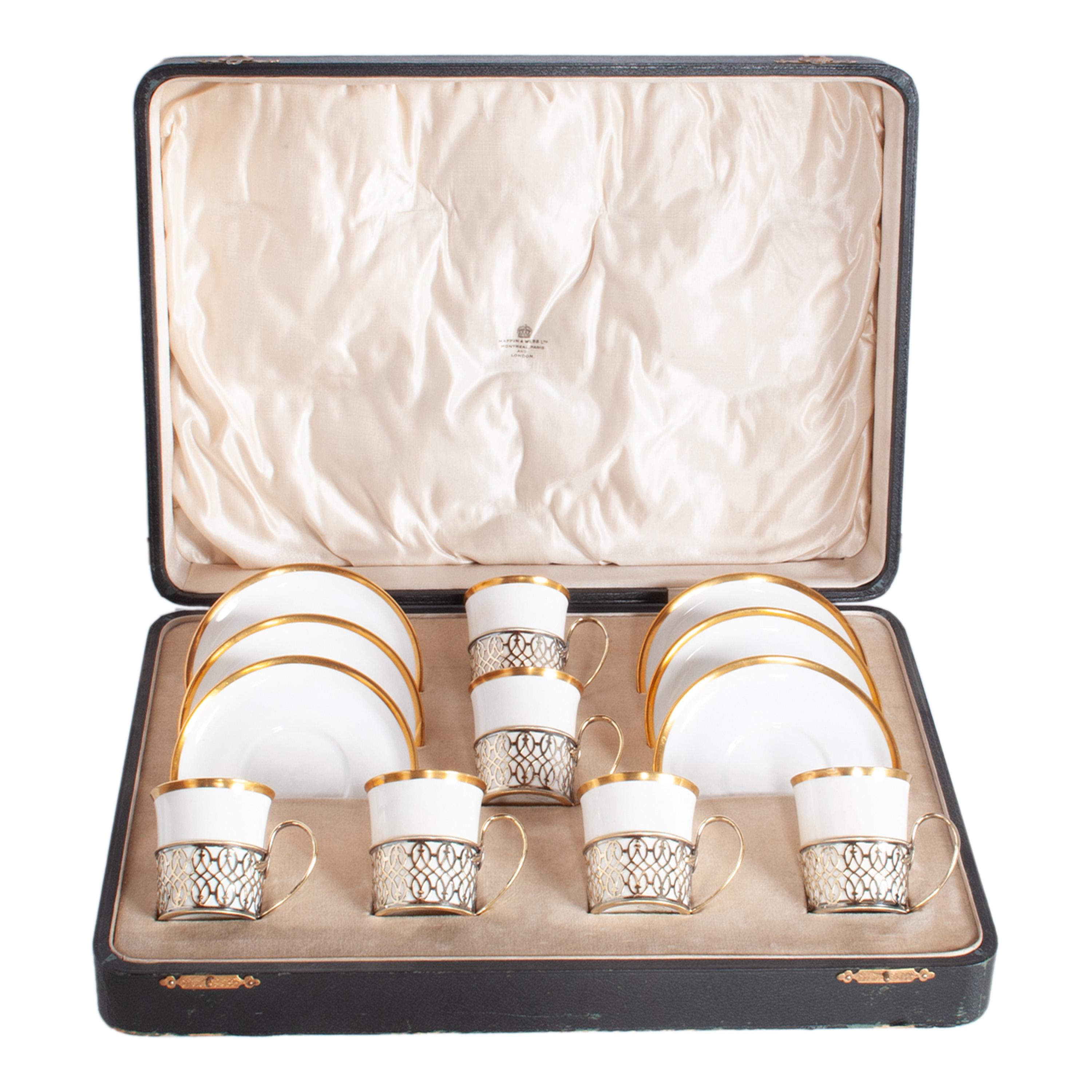 Juego de seis tazas y platillos antiguos de porcelana Shelley con soportes de plata de ley, en caja de buena presentación, de Mappin & Webb, Birmingham, 1919.
Las tazas y los platillos están esmaltados en color marfil y tienen un borde dorado de 24
