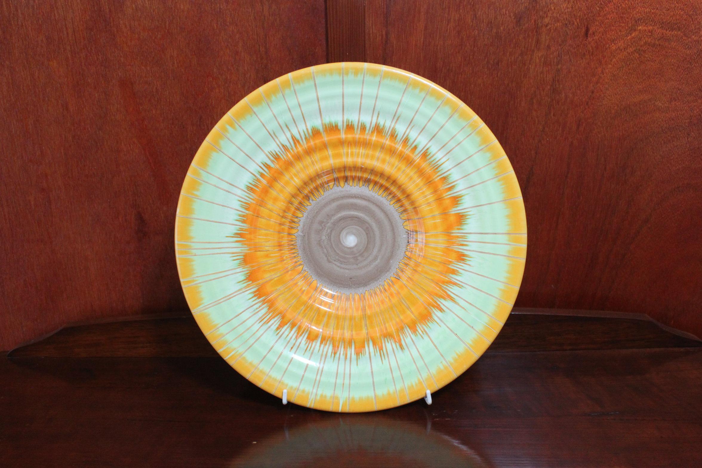 This large Shelley Harmony Ware wall charger is decorated with a fabulous Art Deco sunburst design-the pattern being 8823A, the A standing for Amber colourway. The way it was decorated was that the powdered colours were mixed with turpentine and