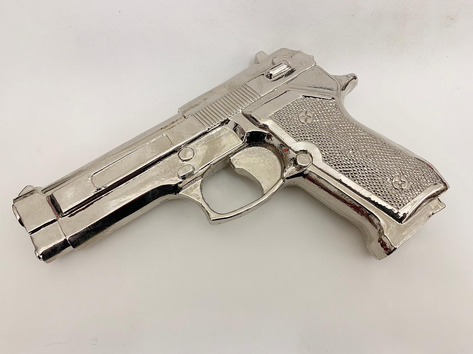 Fake Gun (Beretta)
2017
8” x 5.25” x 1.5” inches 
Cast resin and nickel plating. Unique work.

This sculpture is cast from a replica of the well-known handgun Beretta. It has been transformed into a new object of contemplation that confronts the