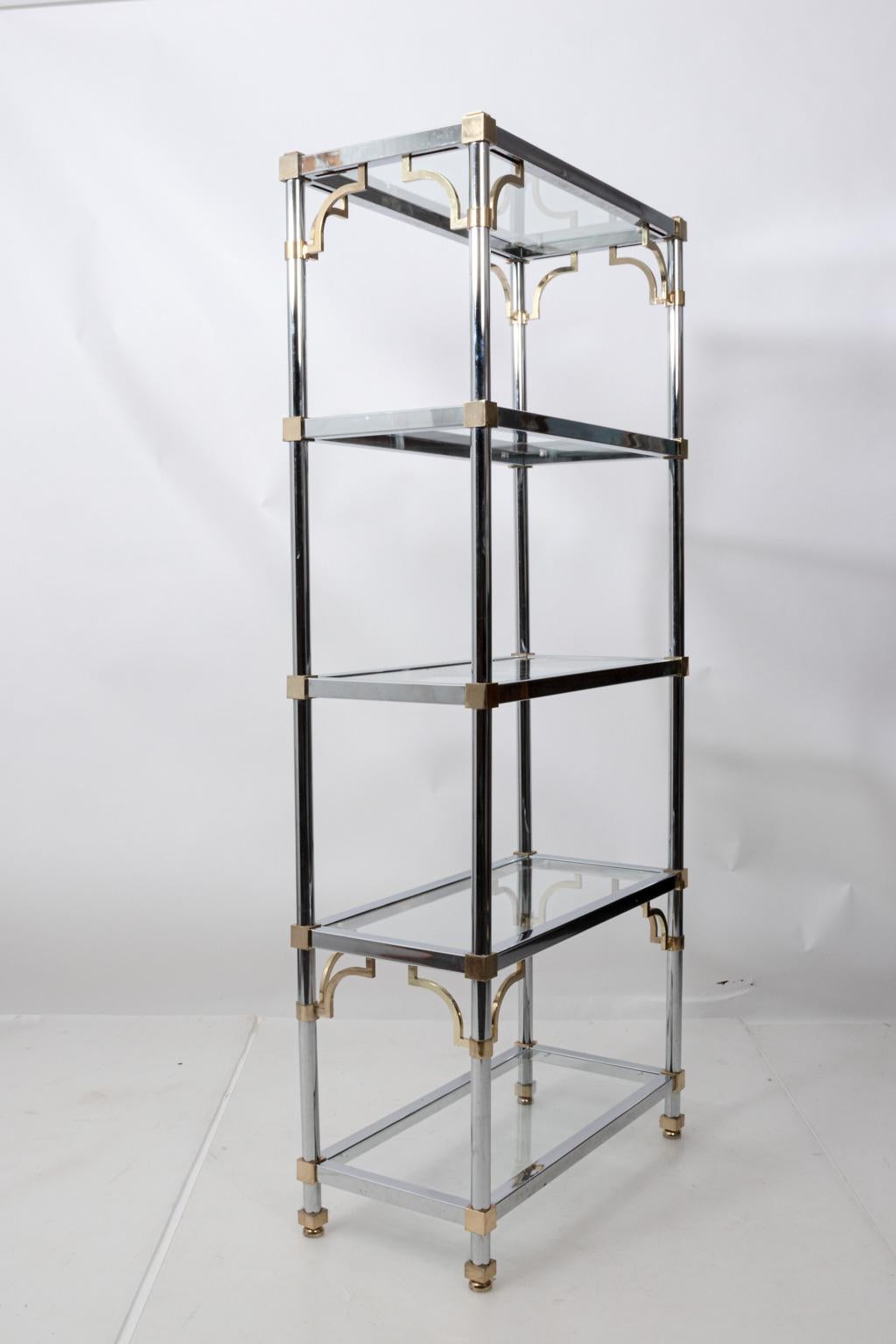 Five-tier glass top shelving unit by Maison Jansen with chrome and decorative brass ornament, circa 1970s. Please note of wear consistent with age including scratches to frame and glass top. One glass shelf is also chipped. Made in France.