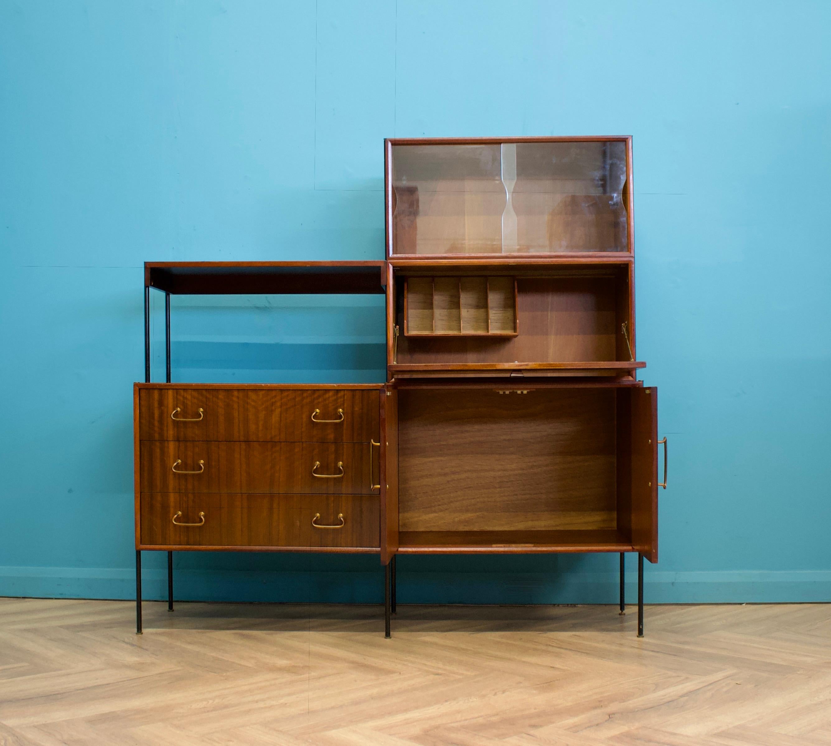 A mid century walnut sideboard shelving unit with a desk designed by Peter Hayward for Vanson, circa 1950s




Featuring two cupboards - one with glass sliding doors.

There's also a pull down desk with storage, a shelf and three drawers.