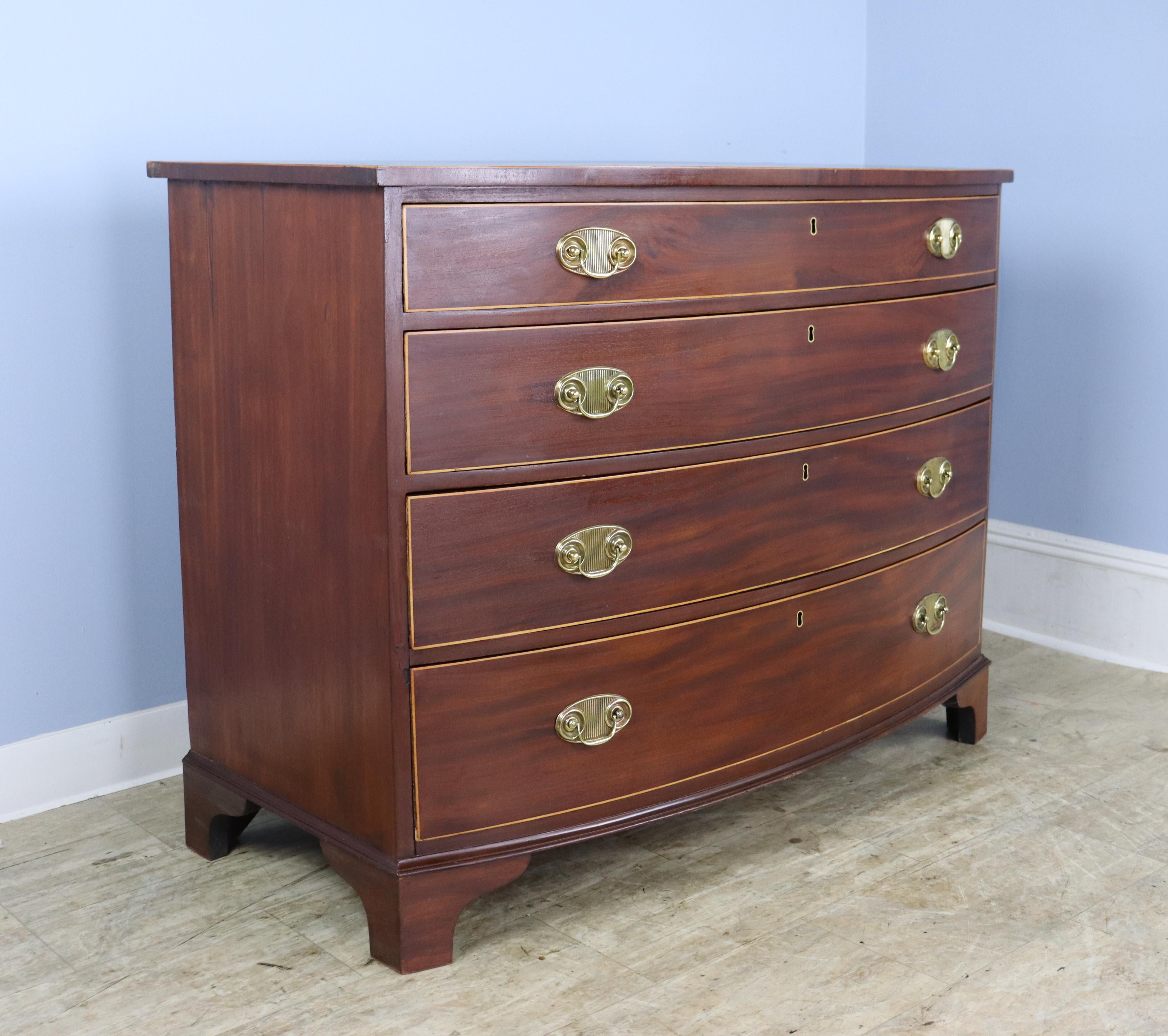 A striking Sheraton bowfront chest of drawers, the Sheraton style being characterized most notably by contrasting veneer inlays. In this piece we have an intricate string of inlay around the top, in good condition, as well as satinwood detail around