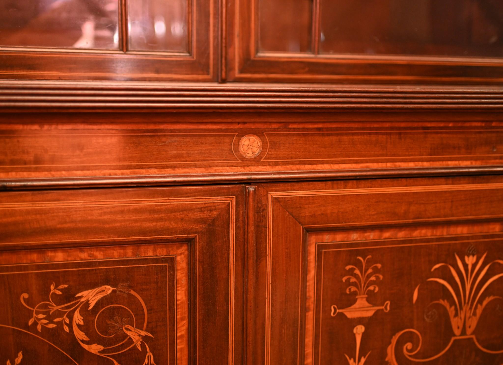 Glorious Sheraton revival mahogany breakfront bookcase 
Grand piece decorated with profuse marquetry inlay
Inlay work includes floral motifs, urns, floral arabesques and other Sheraton motifs
Good size, plenty of storage and display sectin at