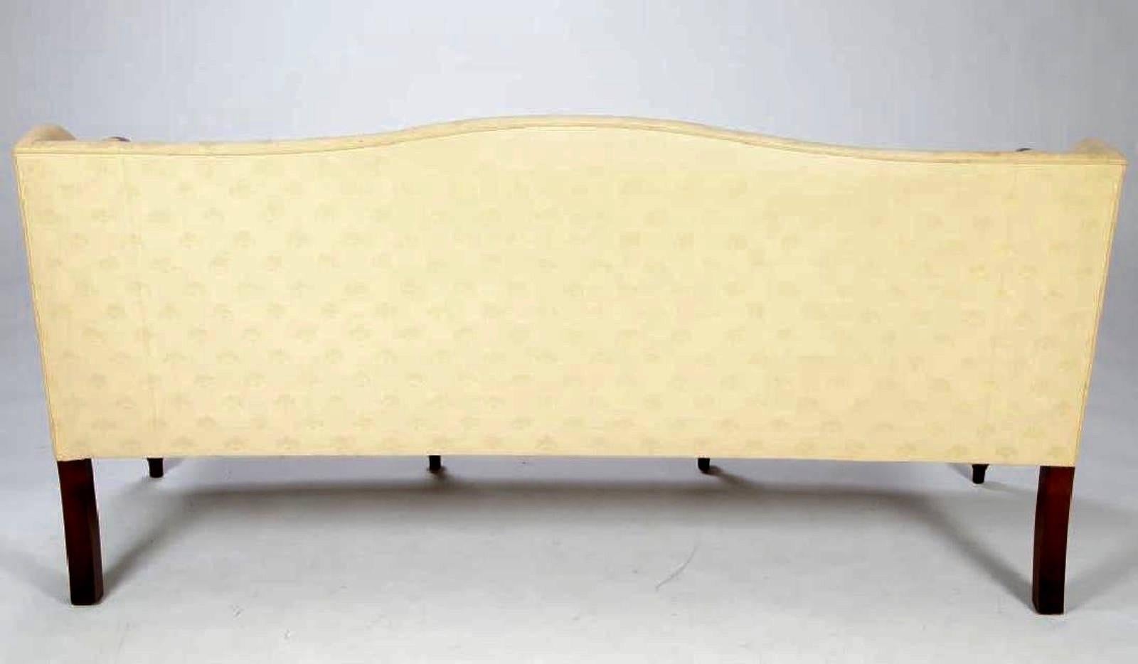 Sheraton Camel back sofa recently reupholstered in a high quality, off white damask with mahogany reeded legs and inlay. Measures: 35 x 71 x 27 inches.


