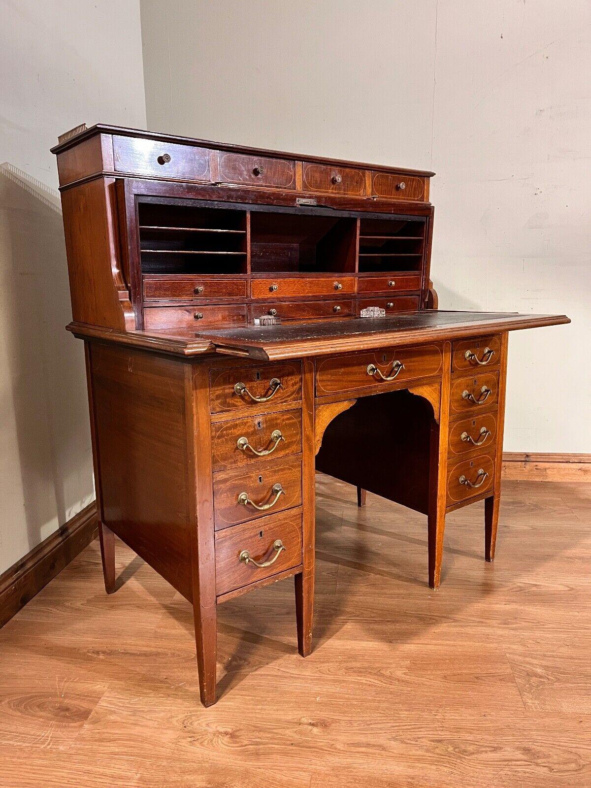 Antique Edwardian roll top desk in the Sheraton manner
Roll top opens up to reveal leather topped writing surface and lots of drawers and cubby holes
Features a brass gallery to the top of the desk
Gorgeous 19th Century antique
Nine drawers around