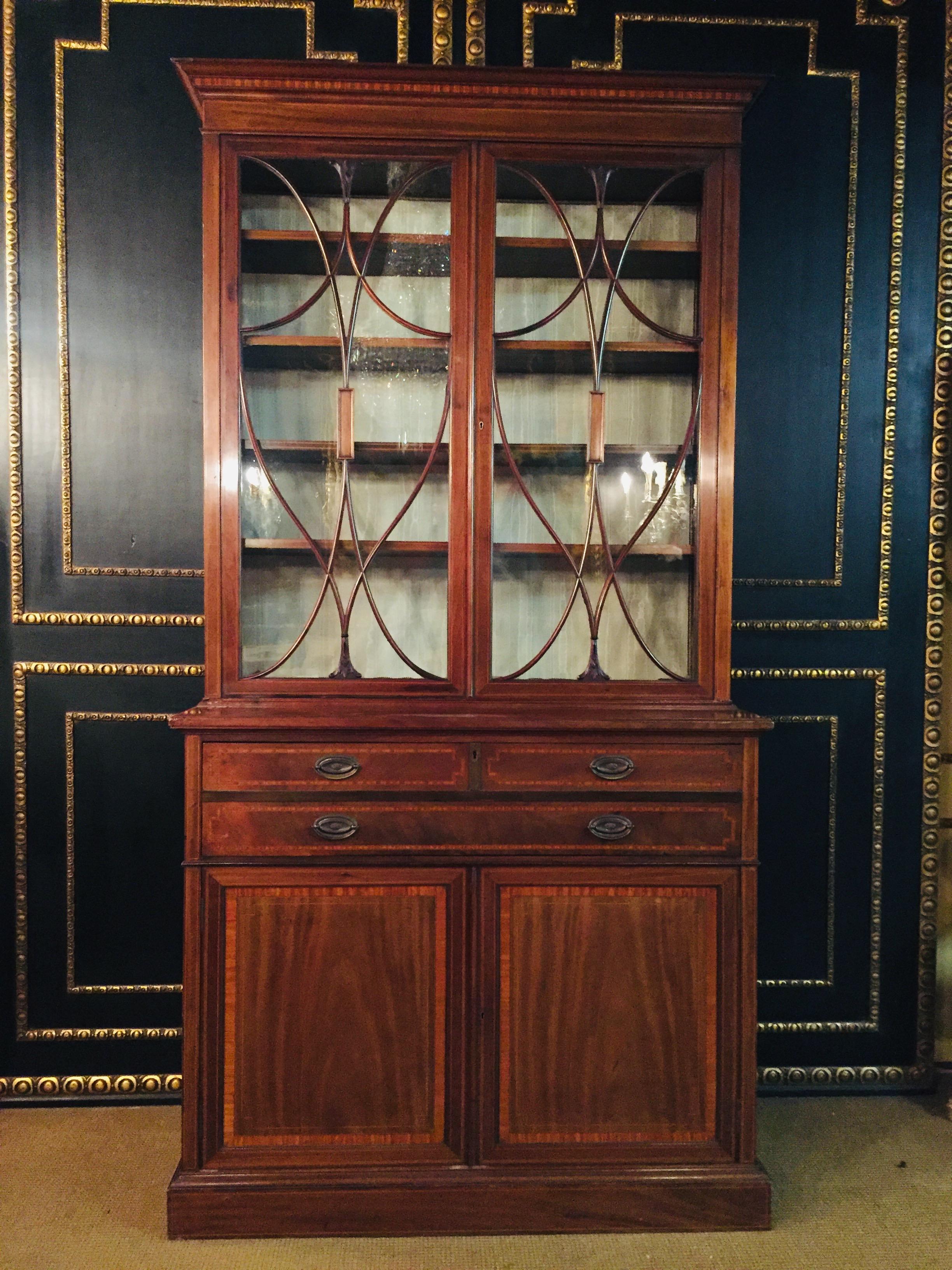 Sheraton mahogany bureau bookcase. With a moulded cornice and glazed and mullioned doors opening to three shelves. A fall-front desk with original brass oval handles opens to folio racks, drawers, and a leather writing surface. All above two paneled