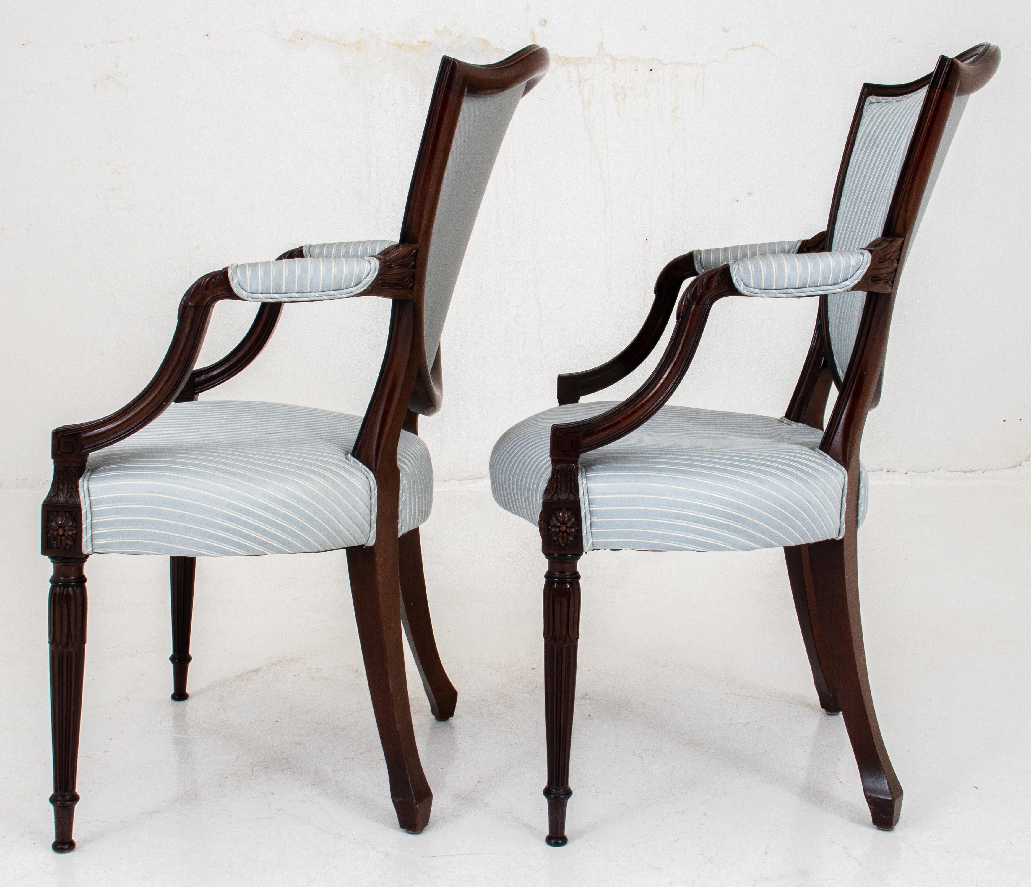 Set of fourteen George III style dining chairs in the manner of Thomas Sheraton, comprising twelve side chairs and two armchairs carved with foliate motif. 

Dimensions: 40