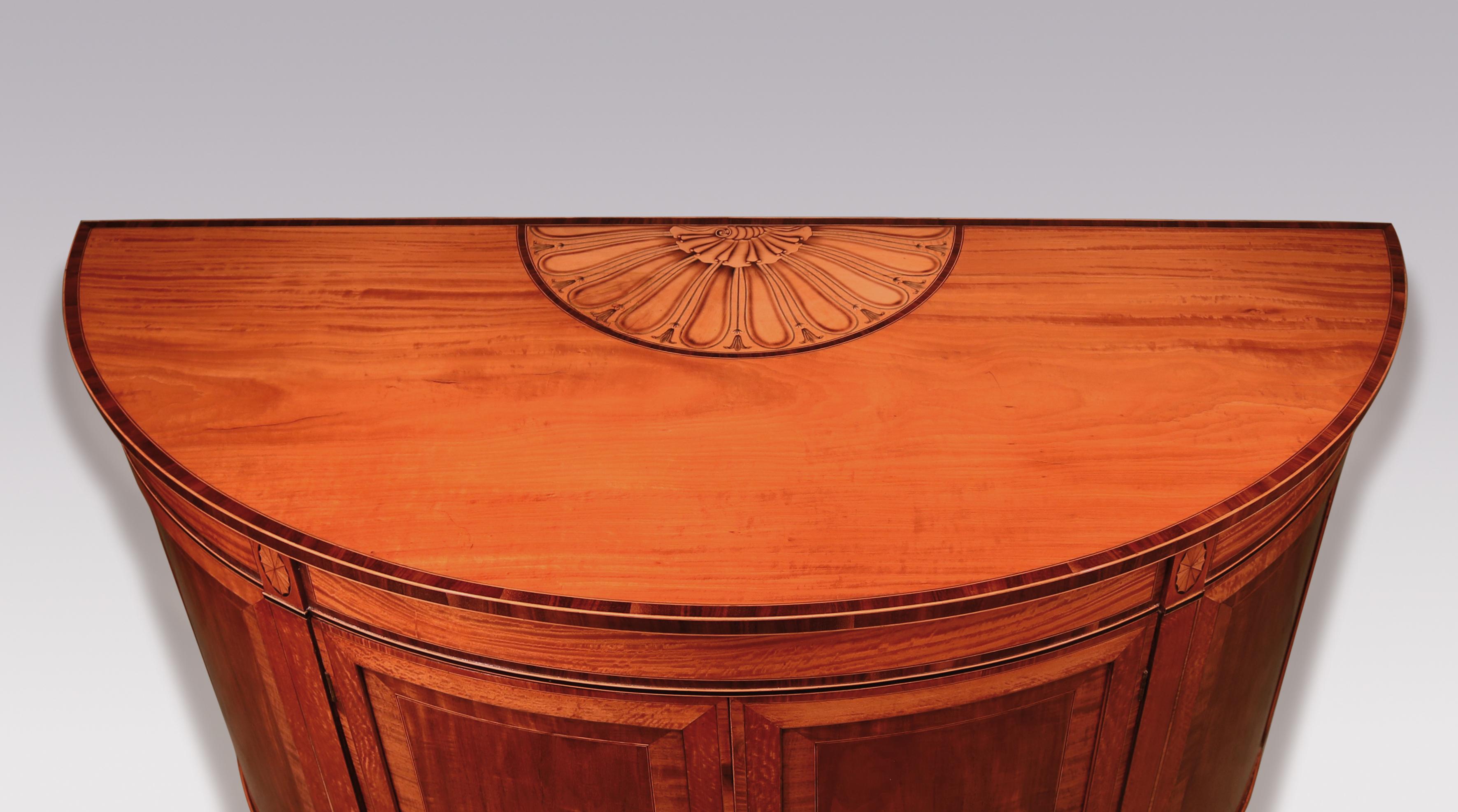 Commode démilune de belle qualité de la fin du XVIIIe siècle de la période Sheraton, en buis et ébène, avec un plateau en bois de Coromandel à bandes croisées avec un panneau central à volutes, coquillages et cosses, au-dessus d'une frise à bandes
