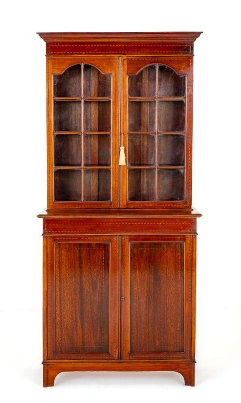 Mahogany Sheraton Revival 2 Door Glazed Bookcase.
Circa 1880
This Bookcase is Raised Upon Stylised Bracket Feet.
The Lower Section Featuring 2 Panelled Doors with Chequred Inlays.
The Upper Section Haqving 2 Arched Glazed Doors with Astragal