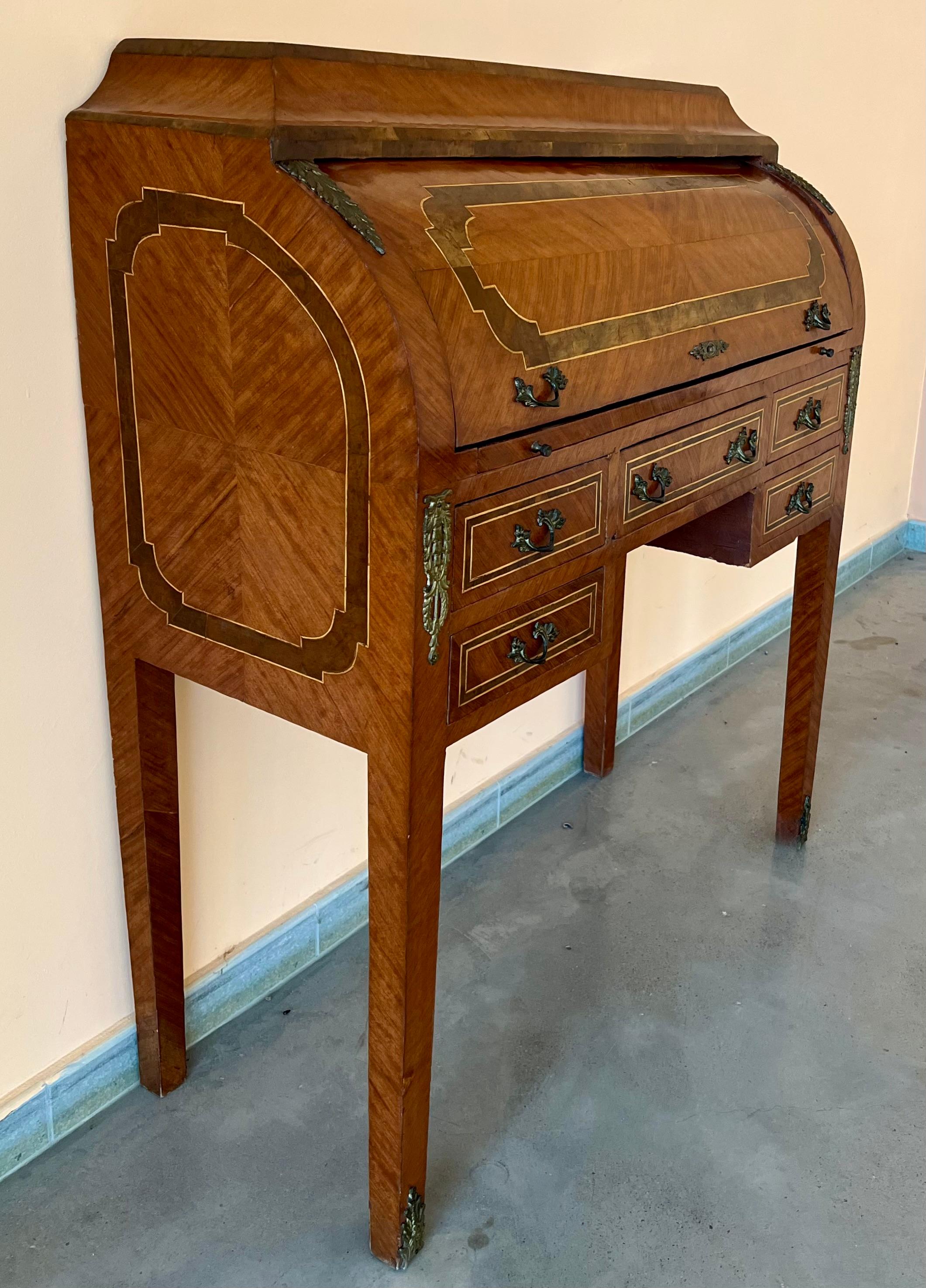 A very good quality late 19th century satinwood Sheraton revival cylinder bureau with ebony string inlay, five walnut frieze drawers, the cylinder opening to reveal pigeon hole compartments within, a sliding inset leather writing tablet, above five