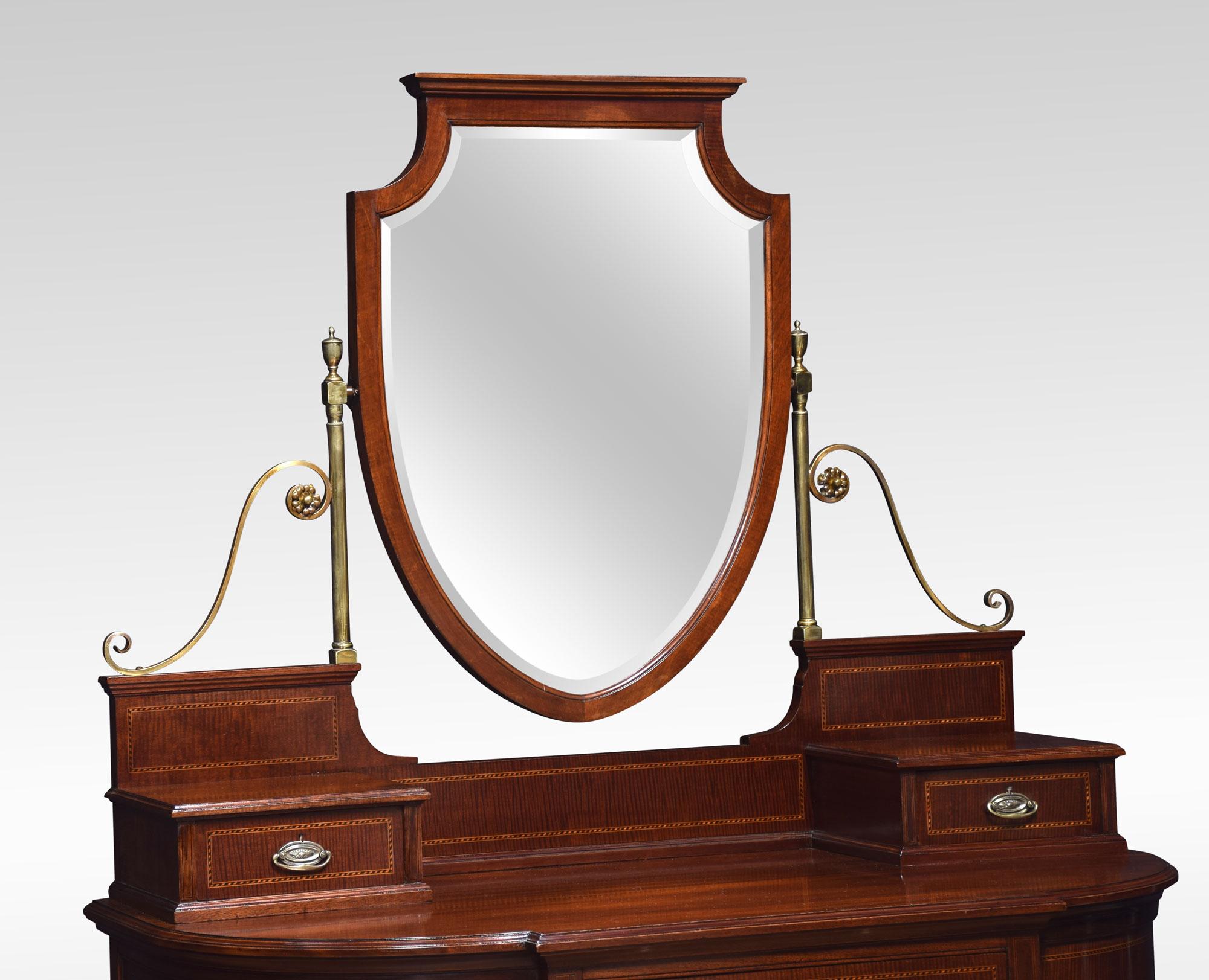 Mahogany dressing table, the superstructure with original shield-shaped bevelled mirror, on brass and scroll supports above two short draws. To the base section with large mahogany top and moulded edge above a central freeze drawer. All raised up on