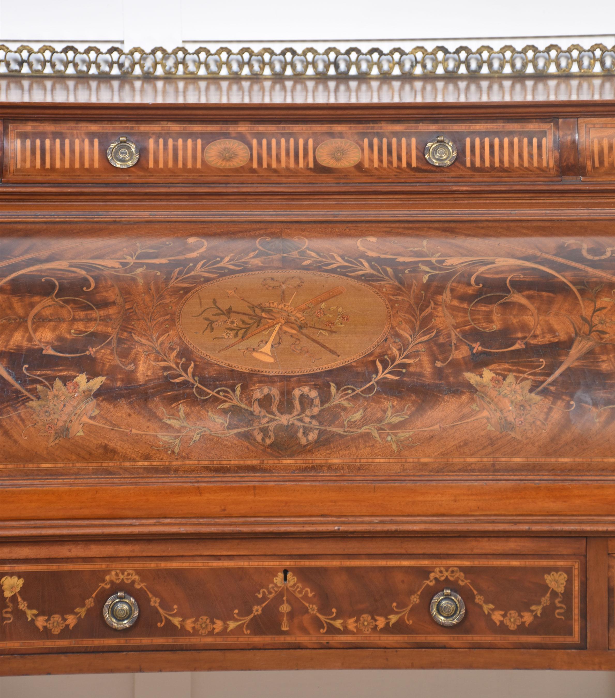 A substantial Sheraton Revival flame mahogany and satinwood crossbanded cylinder bureau, the ornate raised gallery over three cushion frieze drawers with brass tooled handles, above a profusely inlaid cylinder front. The decorative subject matter