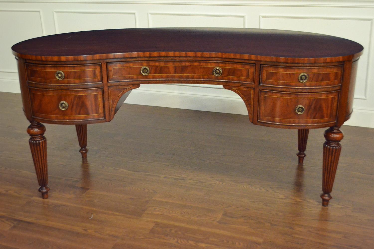 This is a new traditional mahogany library writing desk. Its design was inspired by Sheraton desks from the Regency period and features a kidney shape. The legs are Classic Sheraton style round, fluted and tapered. It also features a top with a