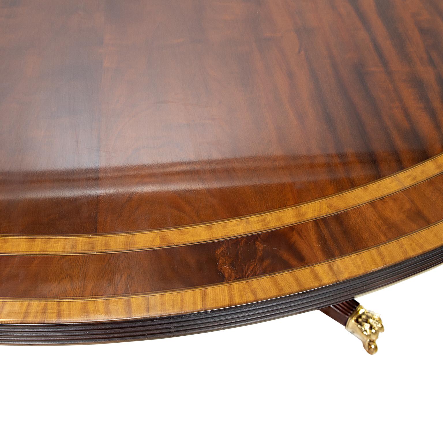 This is a solid mahogany triple band dining table in the Sheraton style. Fine figured grain pattern to the top. The banding is satinwood, walnut, satinwood with ebony string inlay dividing each banding. The top rest upon a birdcage base with four