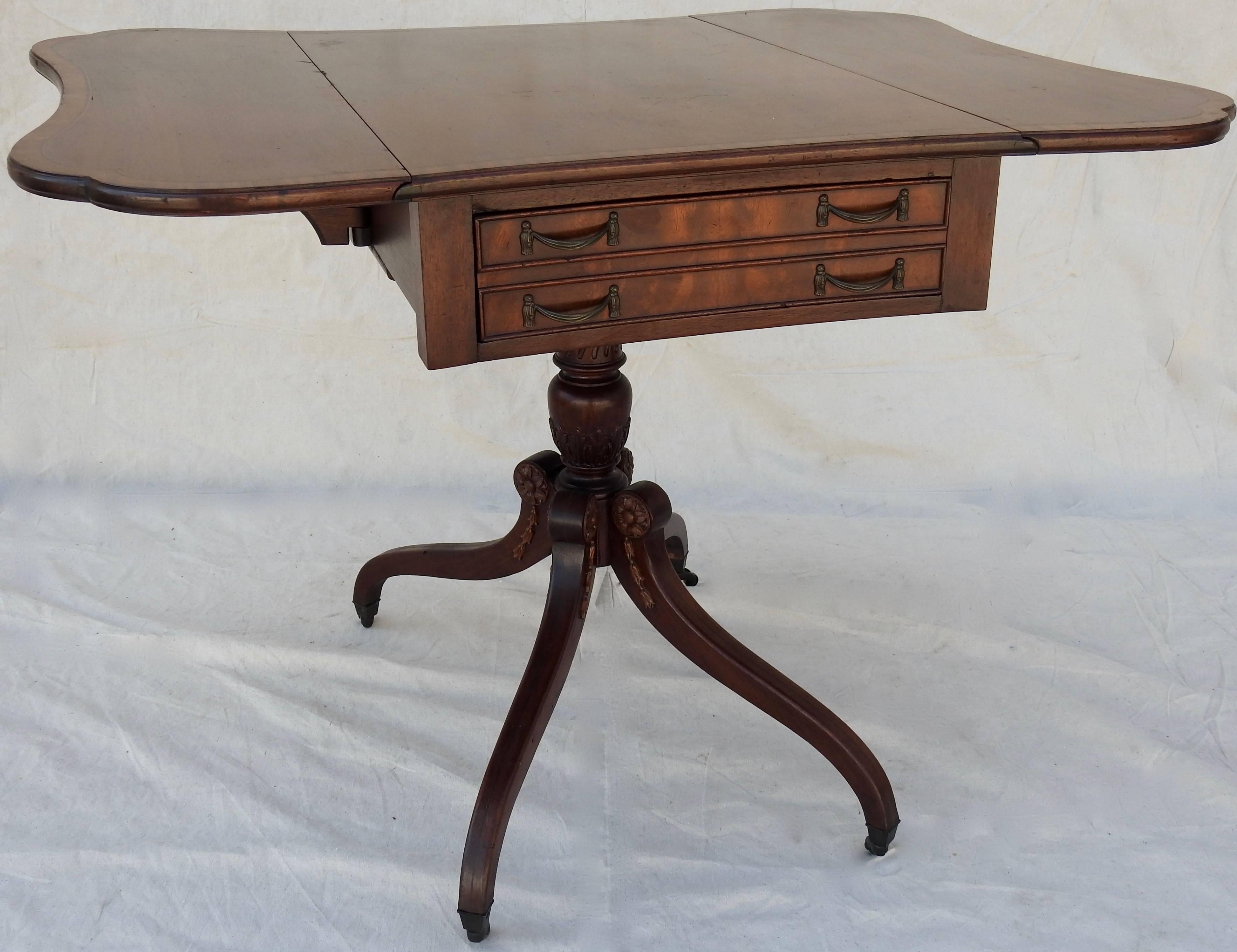 We are offering a unique butterfly shaped drop-leaf table. It is made of walnut with the edges trimmed with inlay. The one drawer is enhanced with cast bronze pulls with tassels. The table sits atop a swirled column with four curved legs that extend