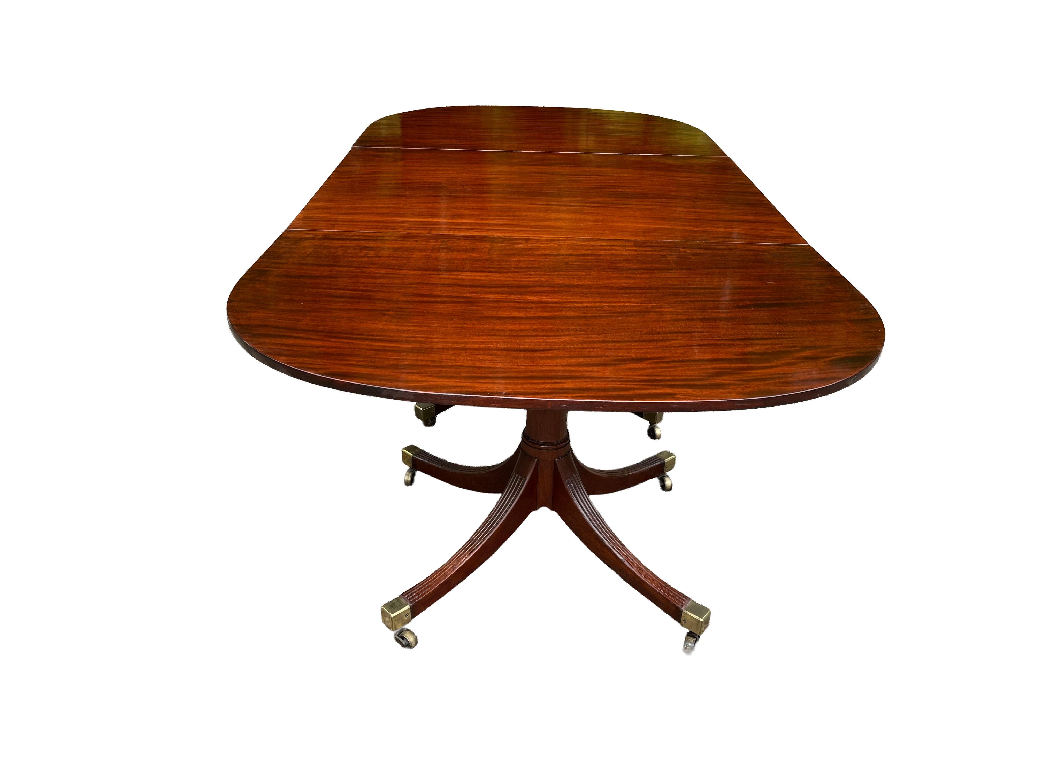 Remarquable table de salle à manger à trois colonnes en acajou figuré, avec deux plateaux d'origine. Les plateaux s'inclinent et reposent sur de solides colonnes en canon, chacune soutenue par des pieds cannelés et moulurés qui se terminent par des