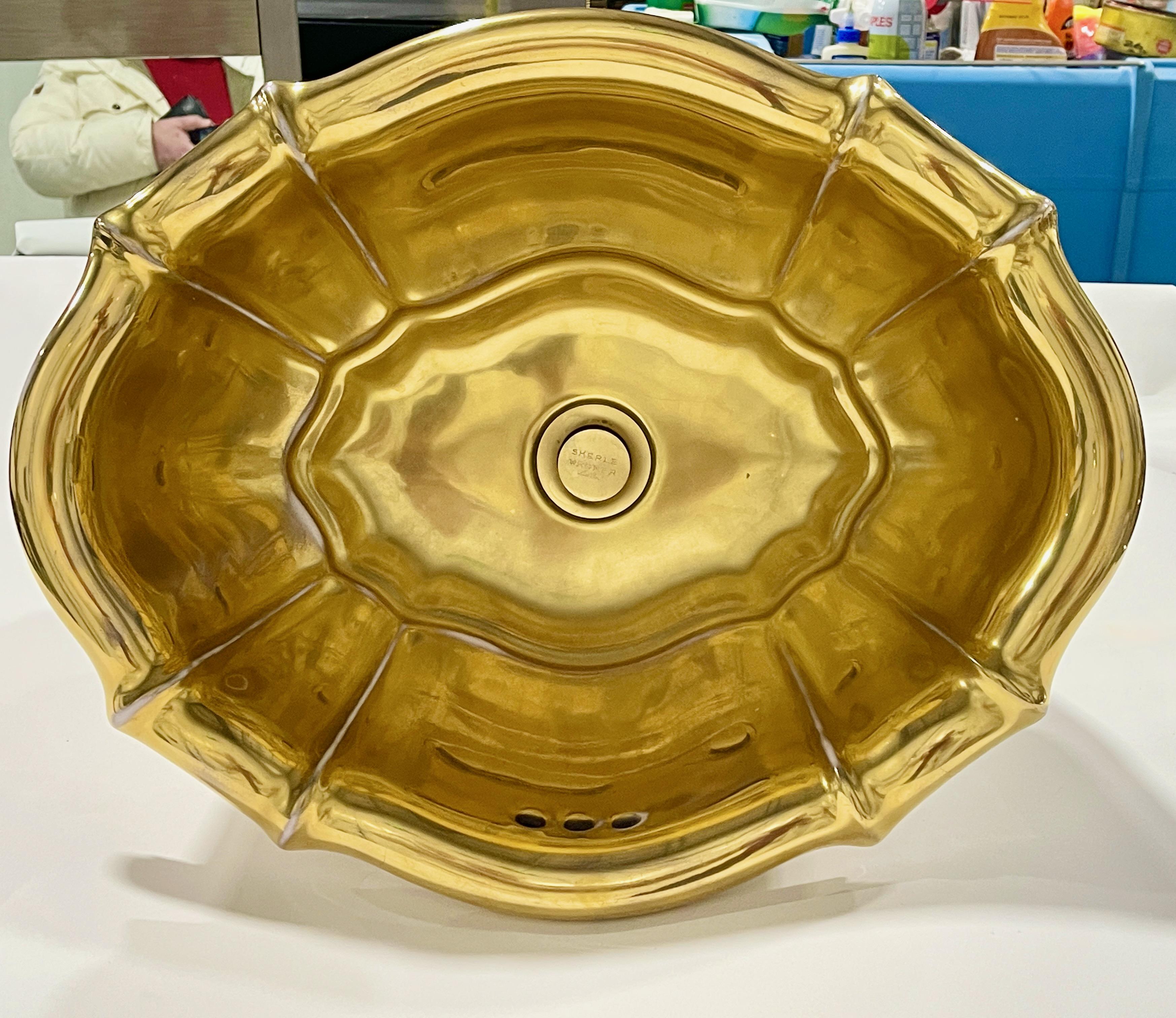 Sherle Wagner gold decorated porcelain sink, scalloped oval form, over edge, counter inset. 
Labeled to porcelain: Sherle Wagner Italy. 
Brass drain also labeled Sherle Wagner New York.
Affixed to underside of basin is ~5 inch brass